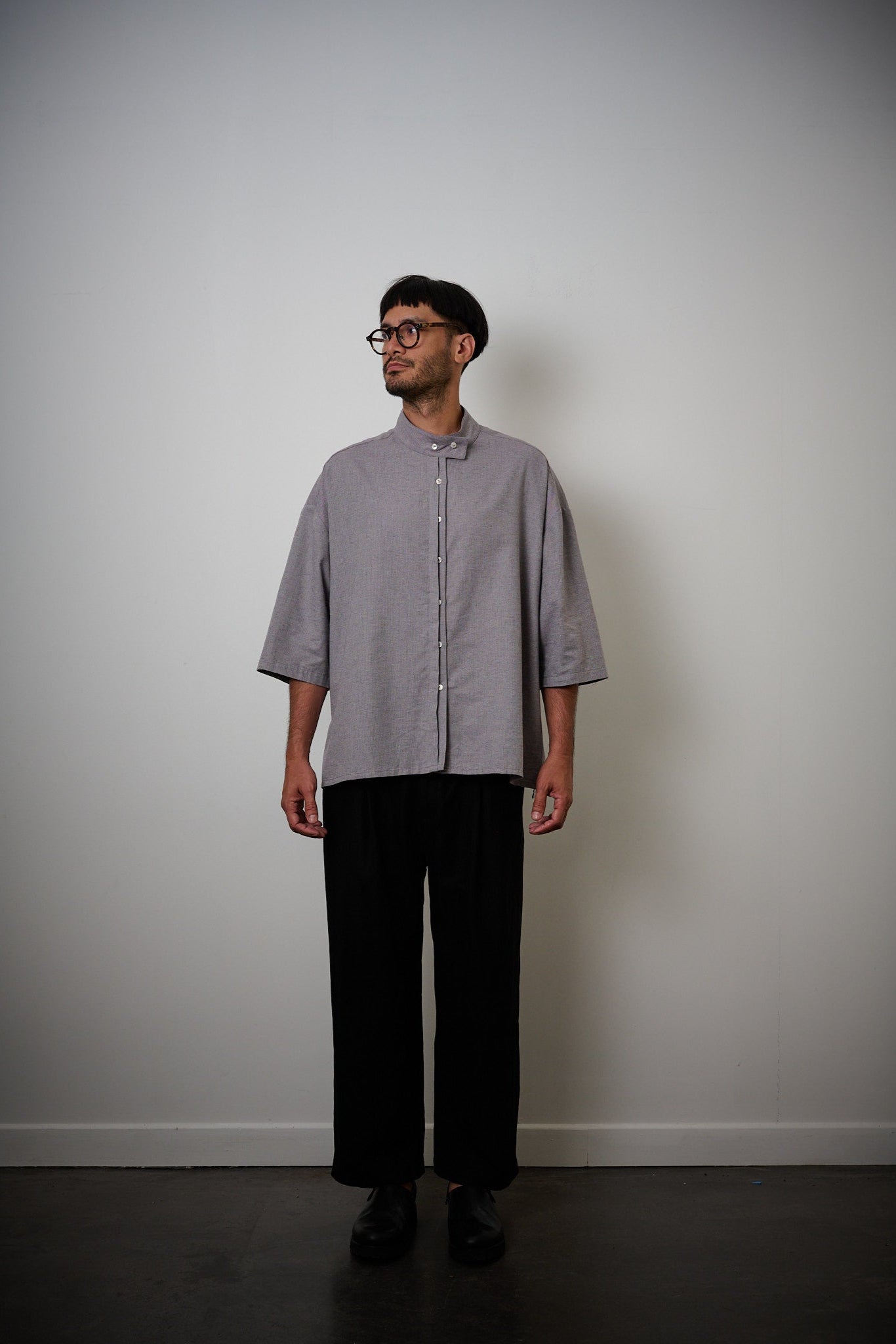 Chemise oversize à manches courtes et col officier de la marque Aïdama, modèle Kita en coton lavande-gris. Portée par un mannequin homme et vue de face.