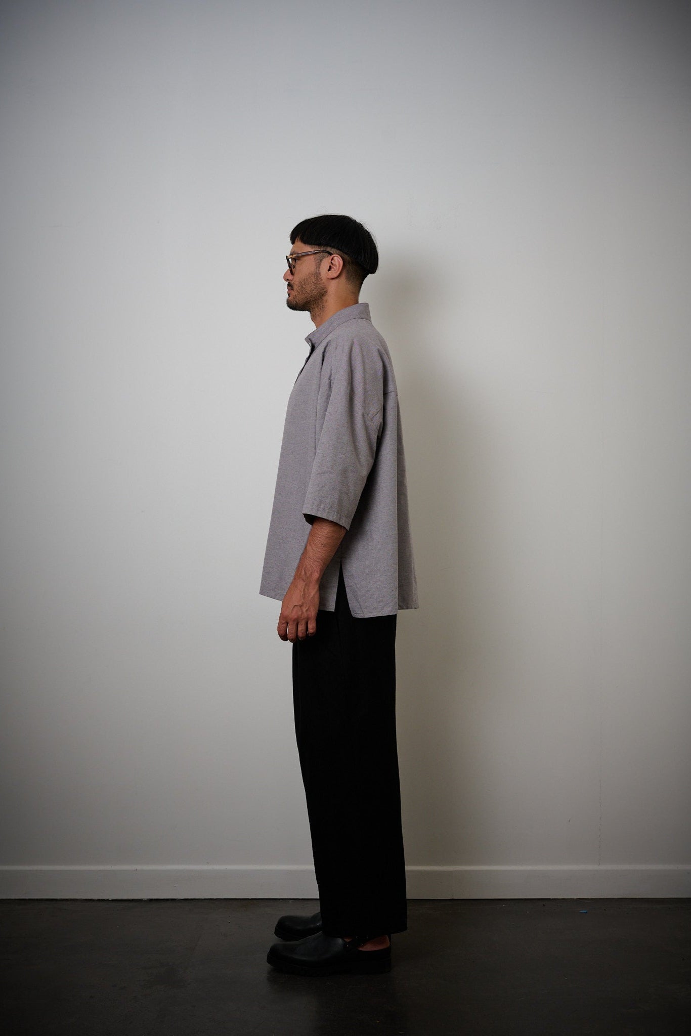Chemise oversize à manches courtes et col officier de la marque Aïdama, modèle Kita en coton lavande-gris. Portée par un mannequin homme et vue de profil.