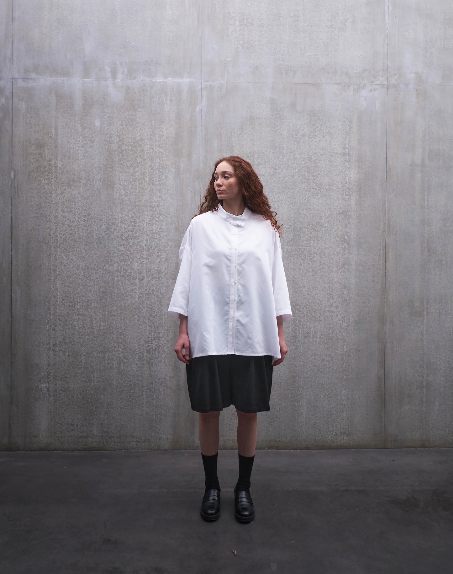 Chemise boxy à manches courtes et col officier Aïdama modèle Kita en popeline de coton blanc. Portée par une mannequin femme et vue de face.