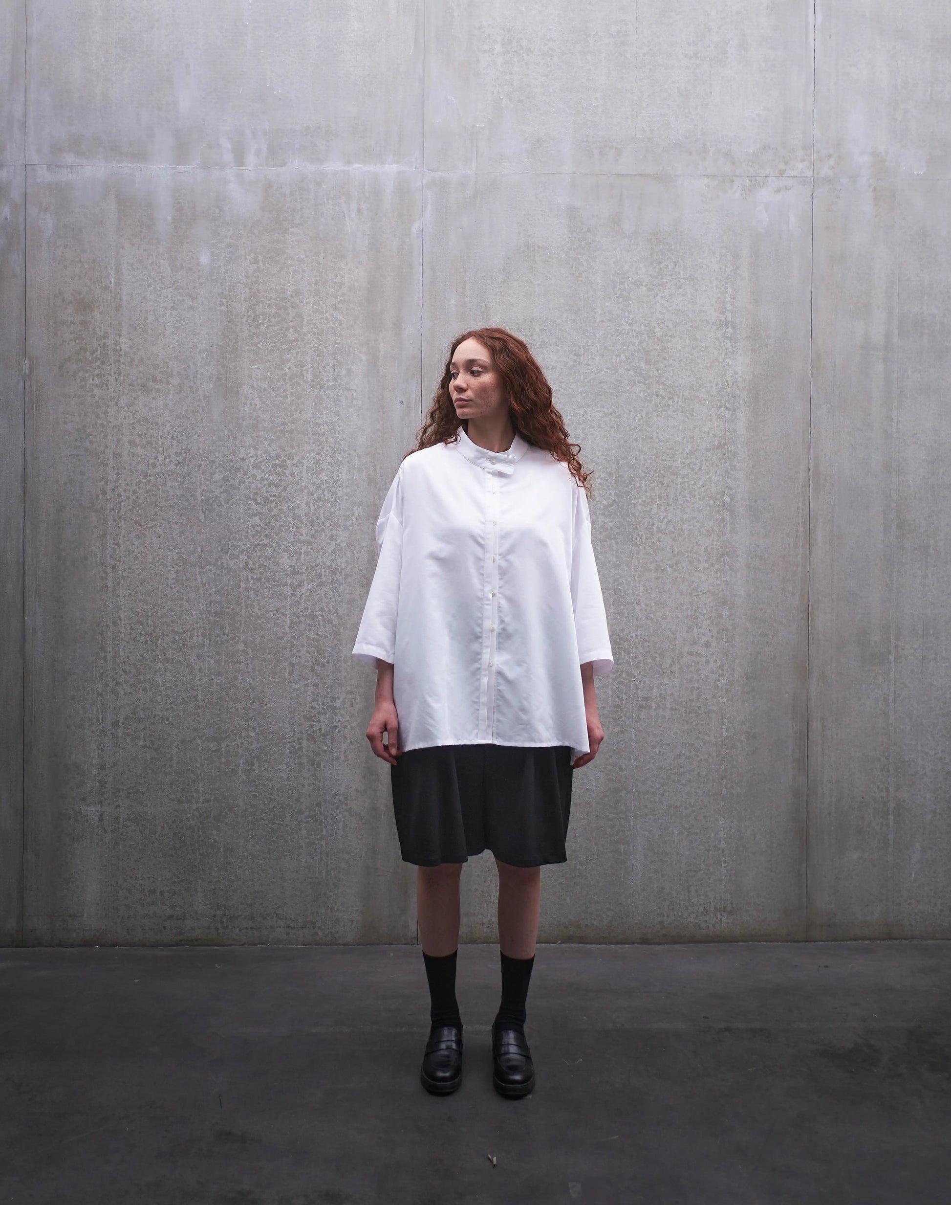 Chemise boxy à manches courtes et col officier Aïdama modèle Kita en popeline de coton blanc. Portée par une mannequin femme et vue de face.