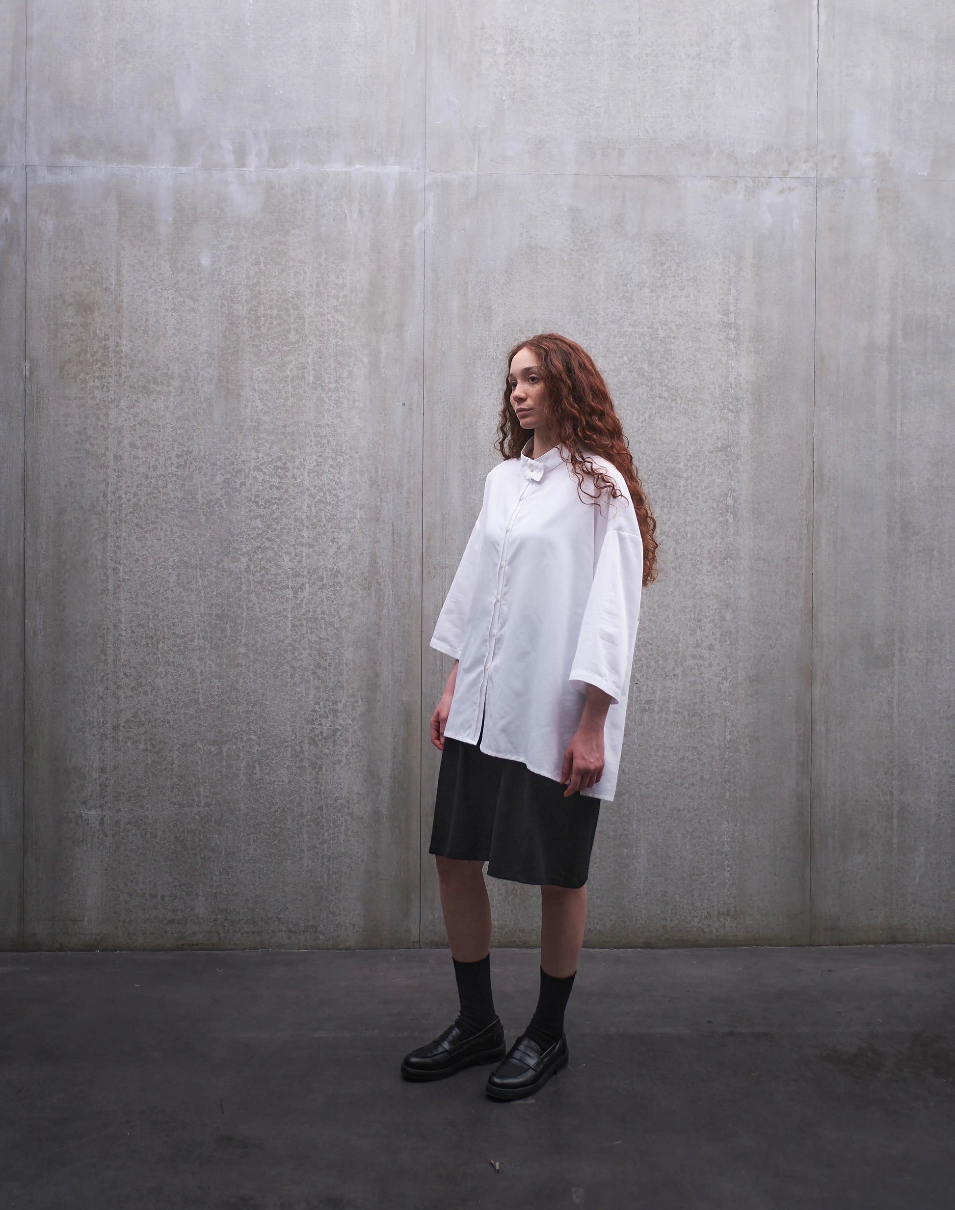 Ensemble short ballon en coton noir à motif Prince de Galles noir ton sur ton et chemise boxy Kita en popeline de coton blanc de la marque Aïdama. Porté par un mannequin homme et vu de dos.