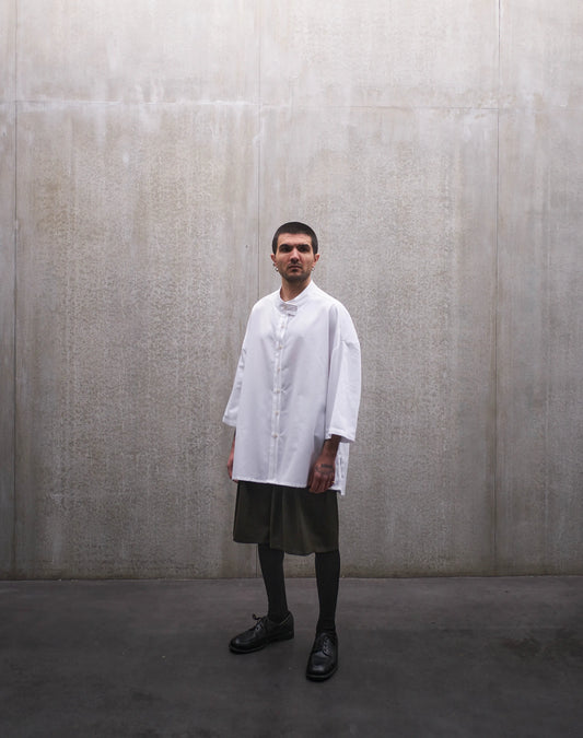 Chemise boxy à manches courtes et col officier Aïdama modèle Kita en popeline de coton blanc. Portée par un mannequin homme et vue de face.