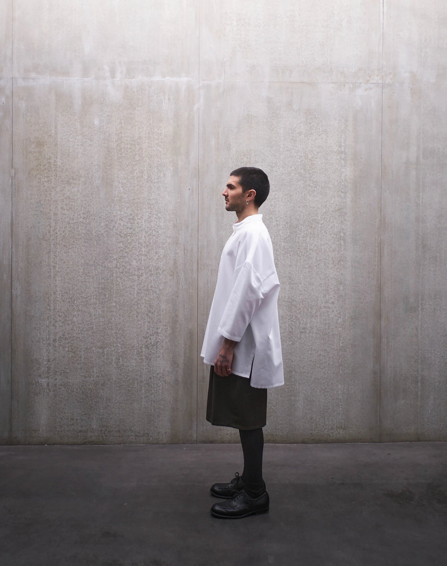 Chemise boxy à manches courtes et col officier Aïdama modèle Kita en popeline de coton blanc. Portée par un mannequin homme et vue de profil.