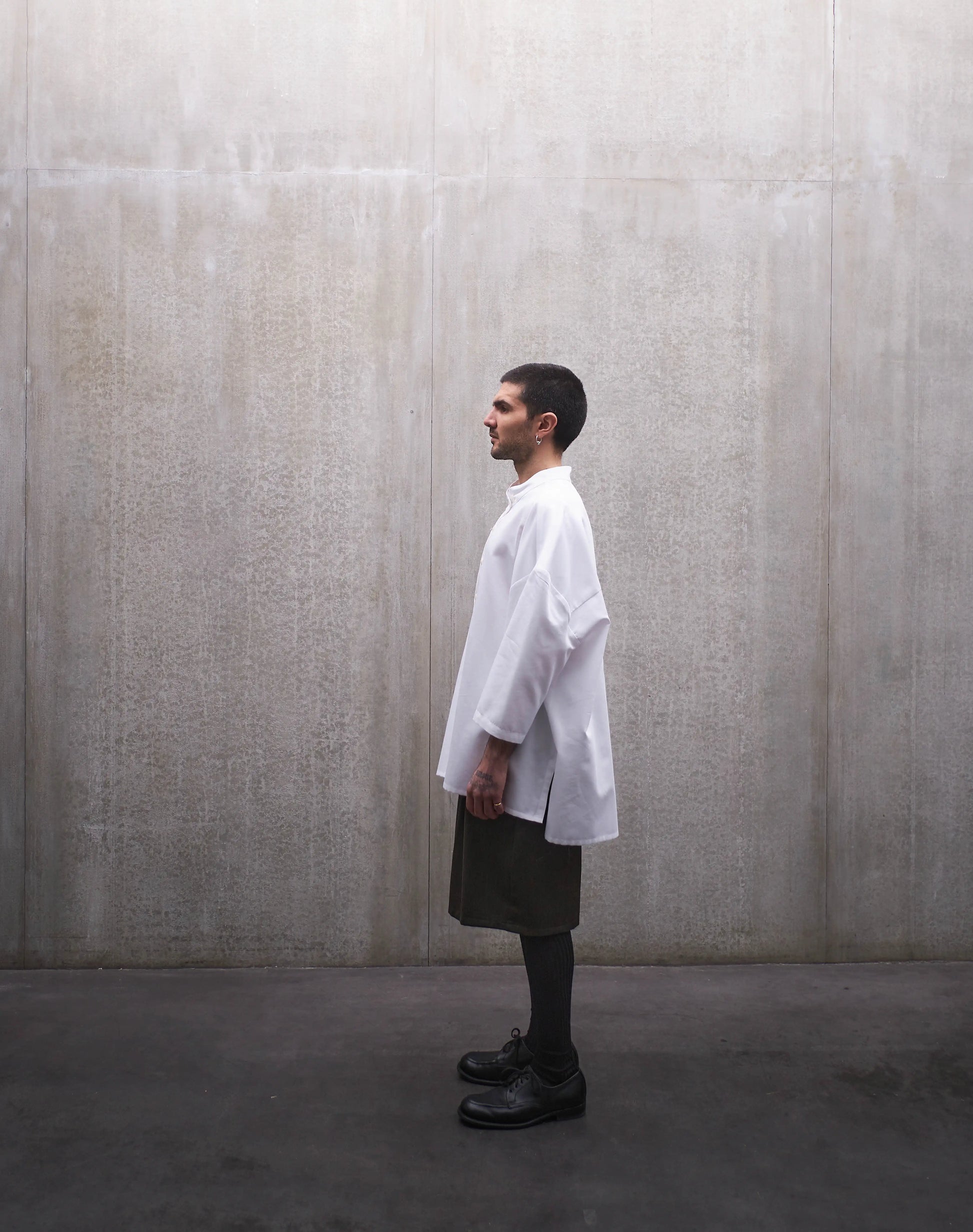 Chemise boxy à manches courtes et col officier Aïdama modèle Kita en popeline de coton blanc. Portée par un mannequin homme et vue de profil.