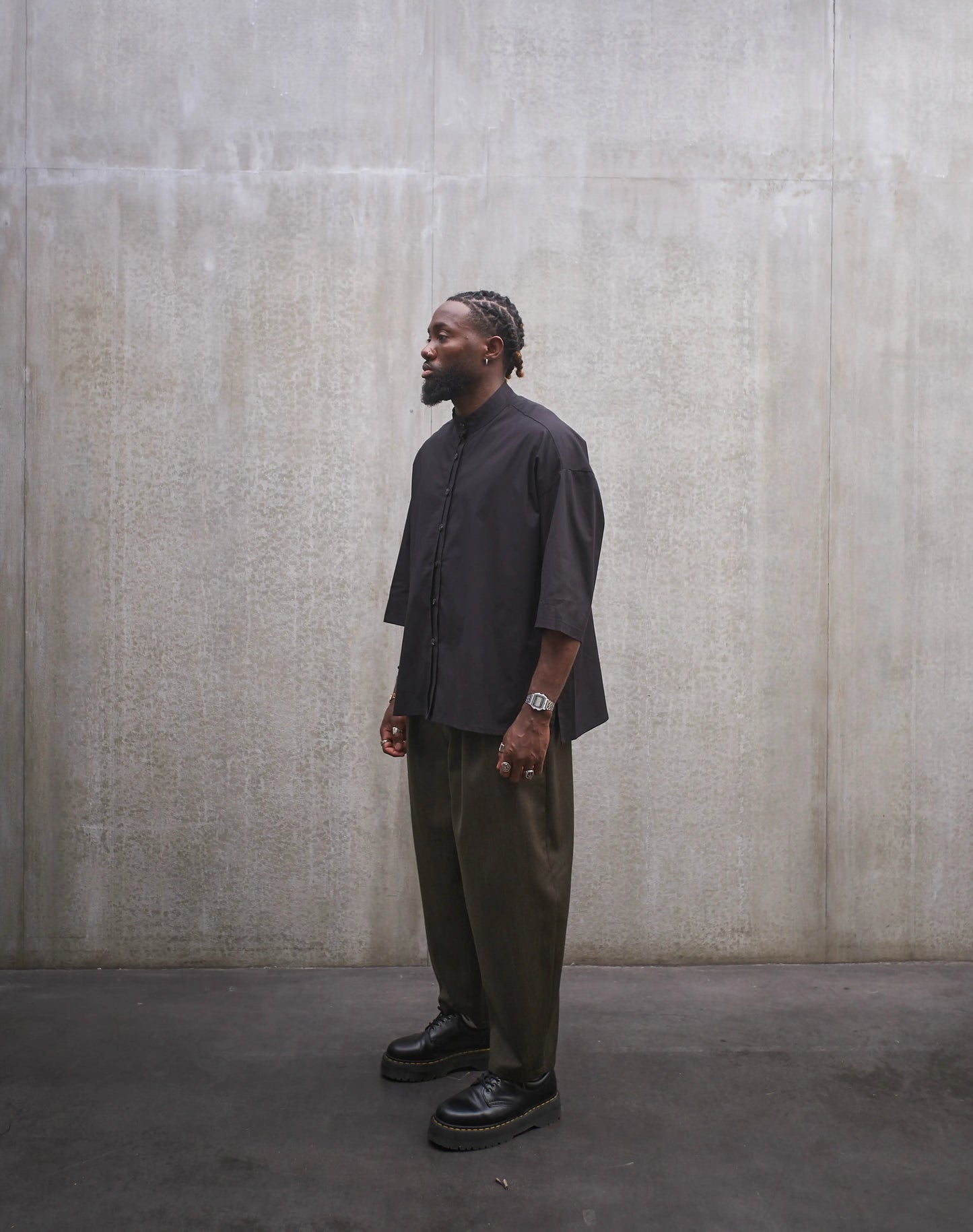 Chemise oversize à col officier de la marque Aïdama, modèle Kita, coupe boxy en popeline de coton noire. Portée par un mannequin homme et vue de trois quarts.