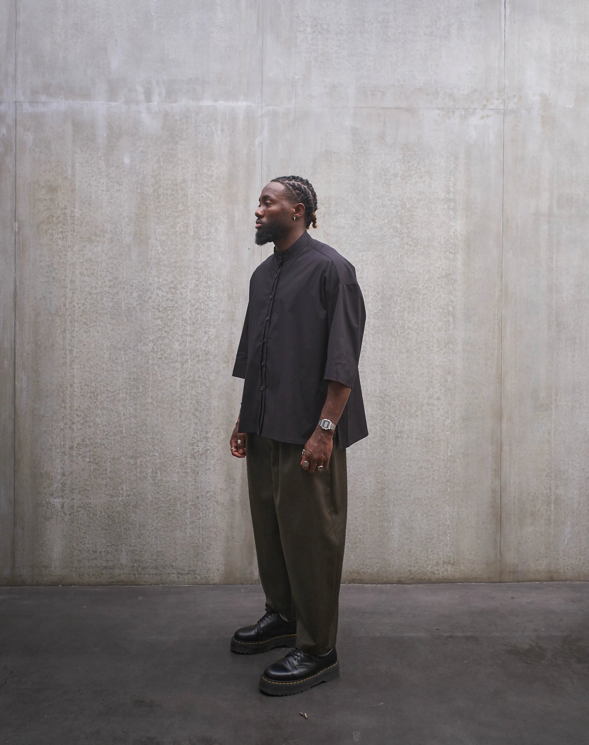 Chemise oversize à col officier de la marque Aïdama, modèle Kita, coupe boxy en popeline de coton noire. Portée par un mannequin homme et vue de trois quarts.