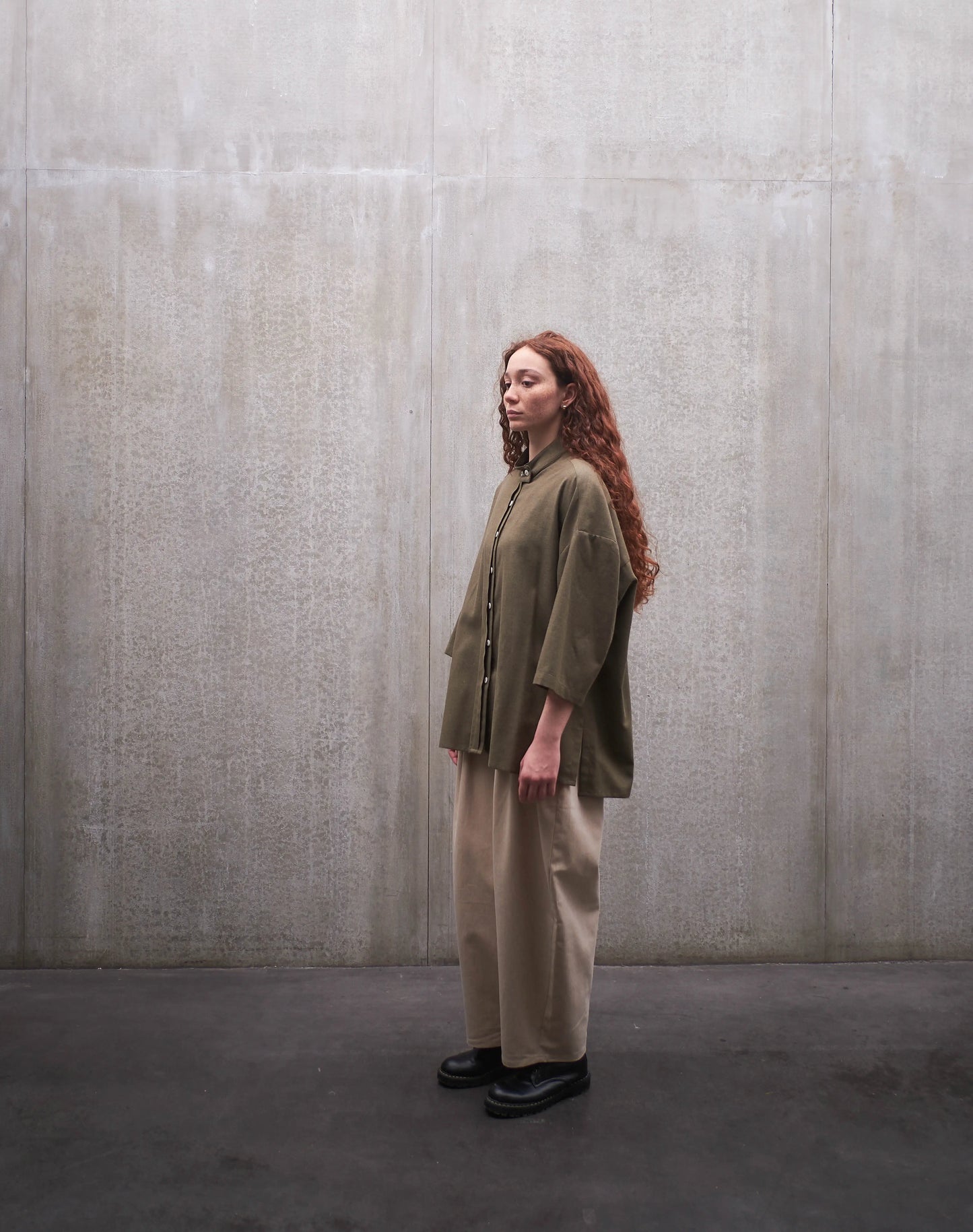 Ensemble chemise boxy à col officier Kita en coton vert chiné et pantalon circulaire, coupe ballon en coton beige de la marque Aïdama. Porté par une mannequin femme et vu de profil.