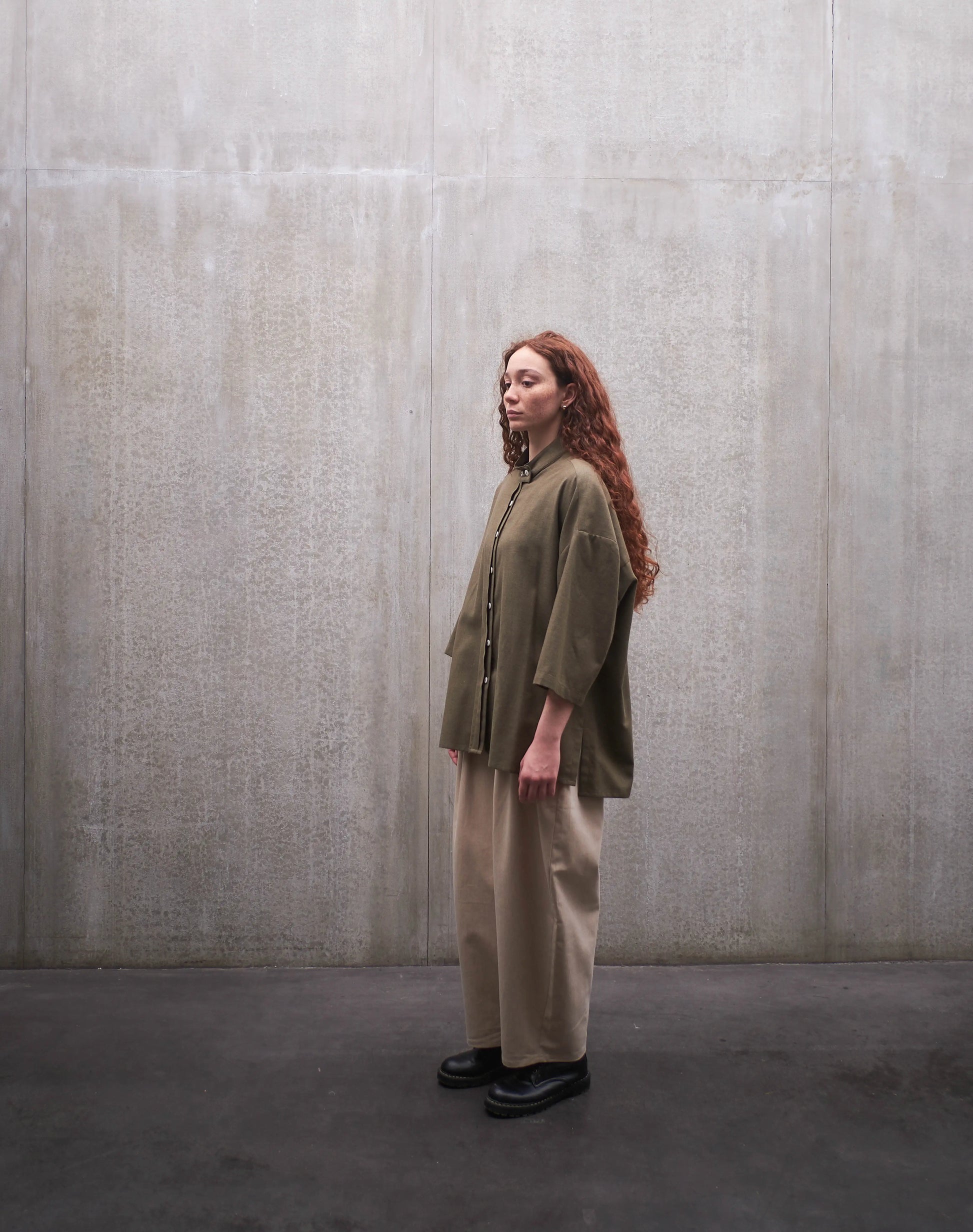 Ensemble chemise boxy à col officier Kita en coton vert chiné et pantalon circulaire, coupe ballon en coton beige de la marque Aïdama. Porté par une mannequin femme et vu de profil.