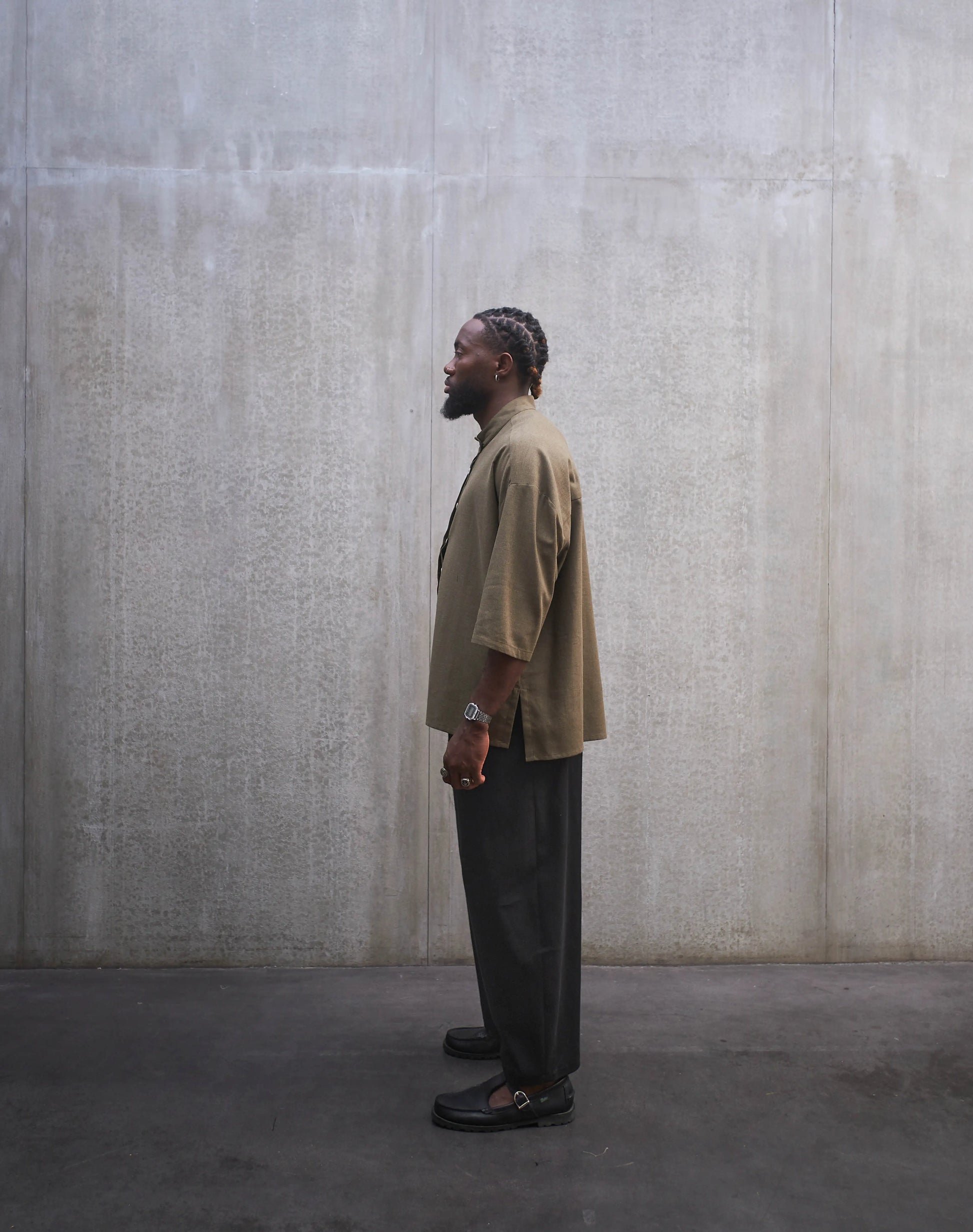 Chemise boxy à manches courtes et col officier Aïdama modèle Kita en coton vert chiné. Portée par un mannequin homme et vue de profil.