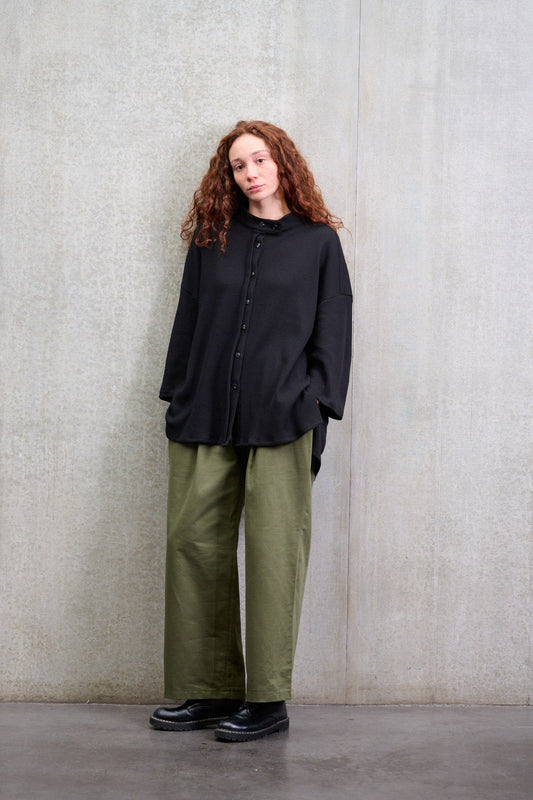 Chemise oversize à col officier, coupe boxy en coton nid d'abeille noir. Portée fermée par une mannequin femme et vue de face.
