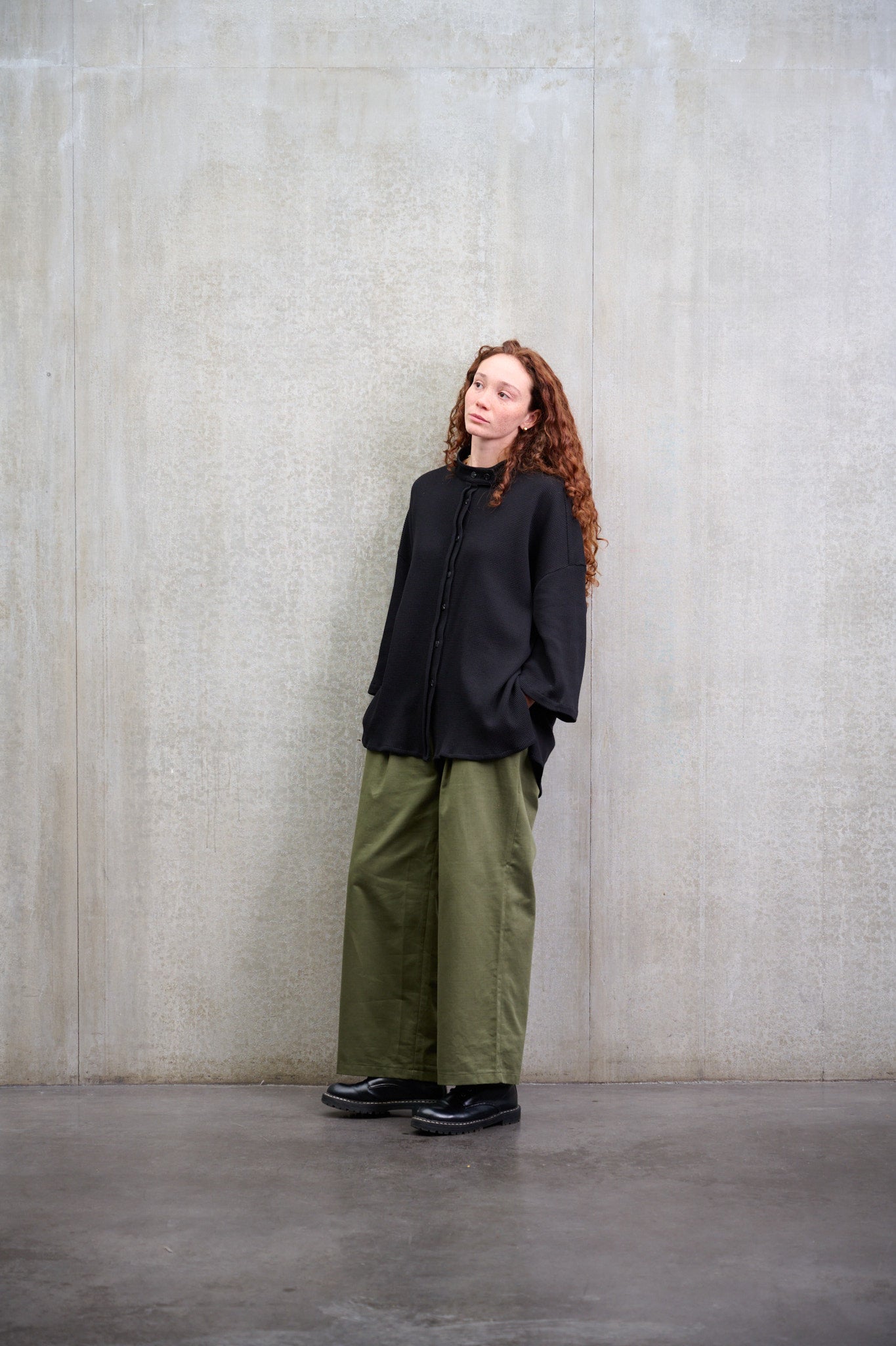 Chemise oversize à col officier, coupe boxy en coton nid d'abeille noir. Portée fermée par une mannequin femme, vue de trois quarts.