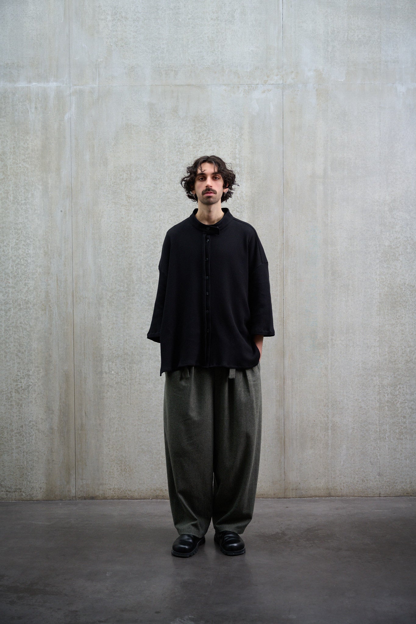Chemise oversize à col officier, coupe boxy en coton nid d'abeille noir. Portée fermée par un mannequin homme et vue de face.