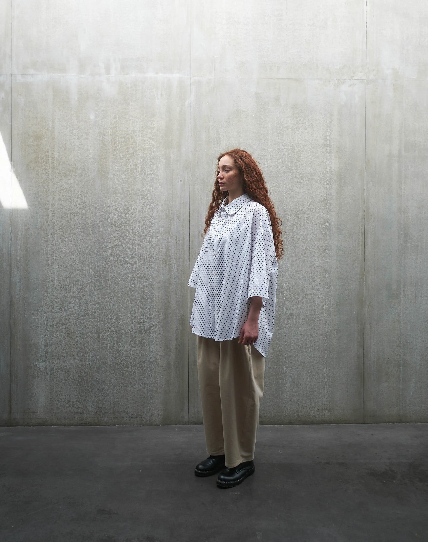 Chemise oversize à manches courtes et col club Aïdama modèle Marui en coton blanc à pois bleus. Portée par une mannequin femme et vue de profil.