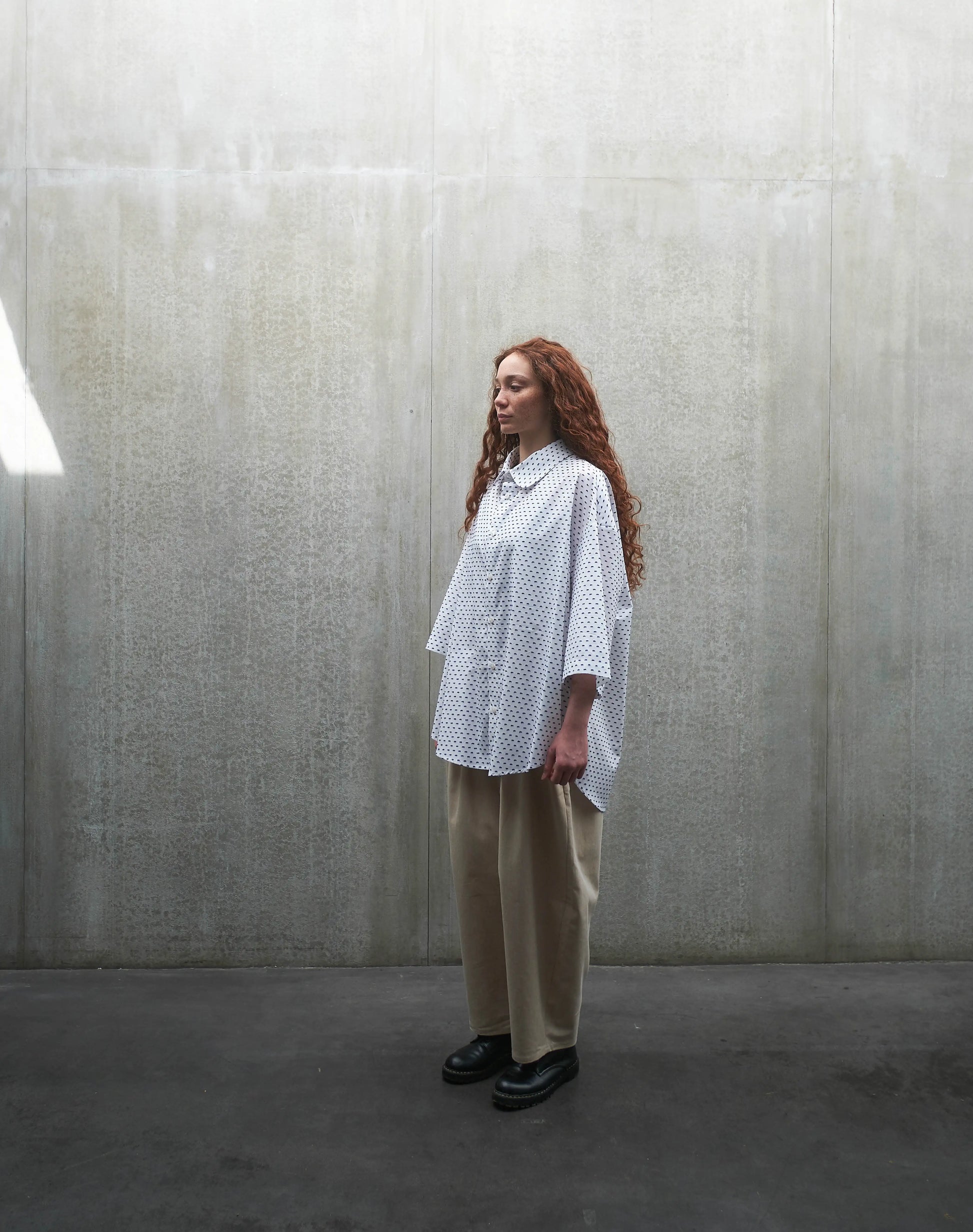 Chemise oversize à manches courtes et col club Aïdama modèle Marui en coton blanc à pois bleus. Portée par une mannequin femme et vue de profil.