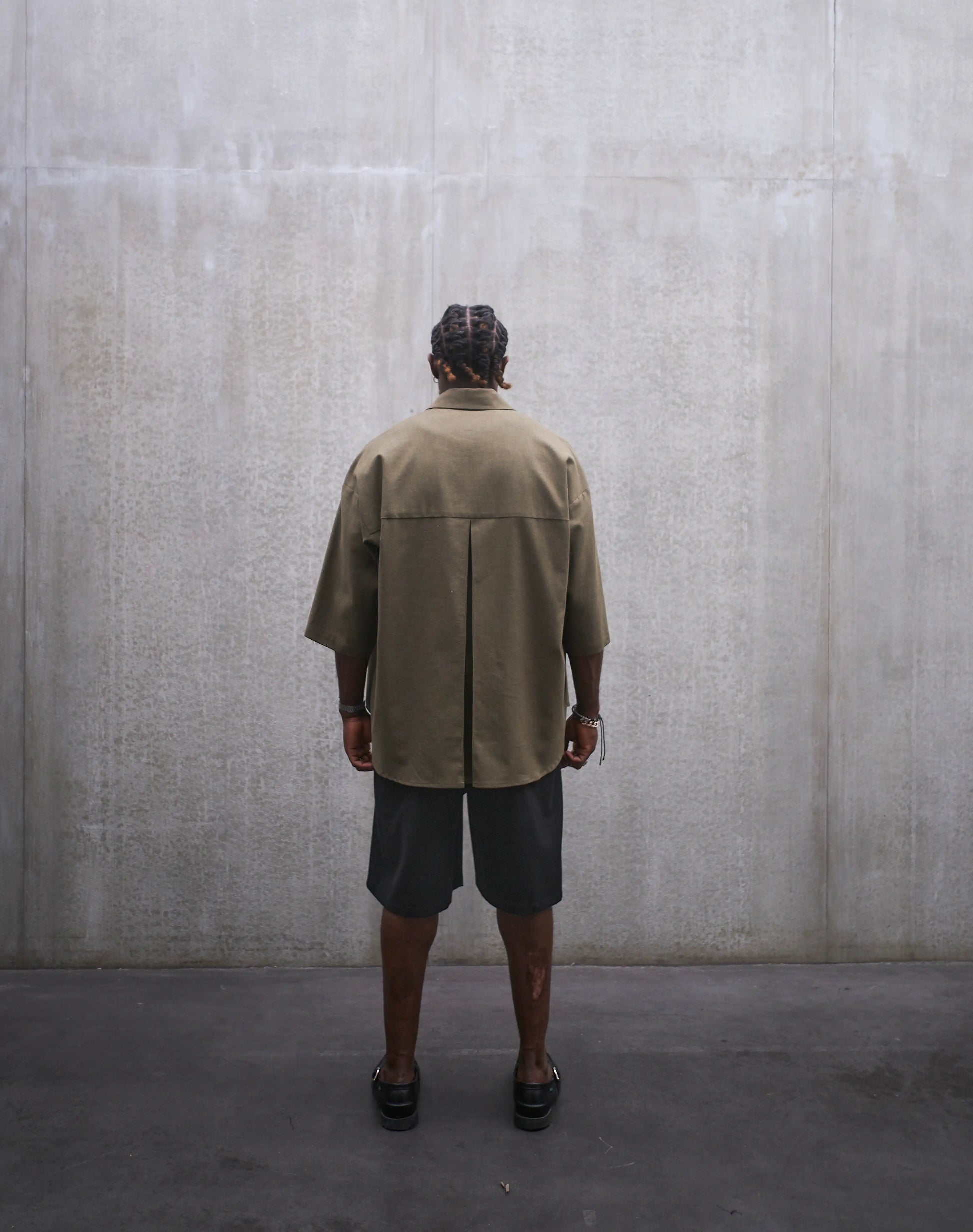 Ensemble short ballon en coton noir à motif Prince de Galles noir ton sur ton et chemise oversize marui en coton vert chiné de la marque Aïdama. Porté par un mannequin homme et vu de dos.