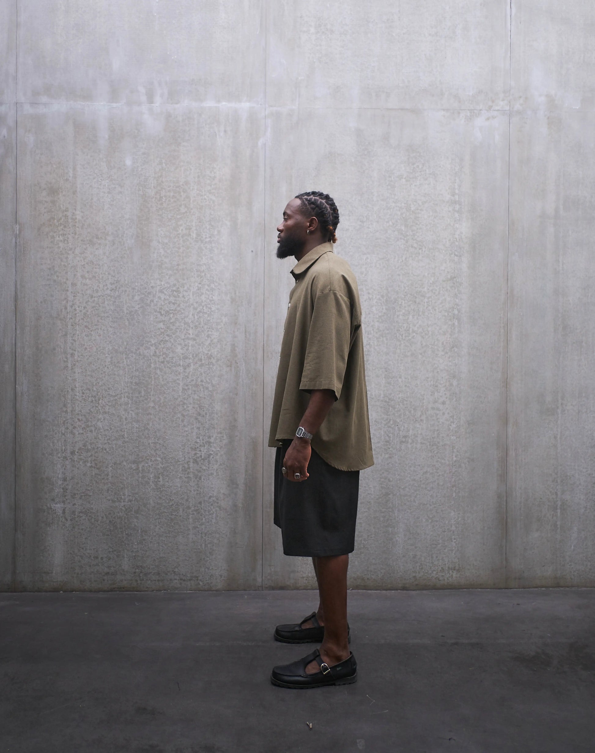 Ensemble short ballon en coton noir à motif Prince de Galles noir ton sur ton et chemise oversize marui en coton vert chiné de la marque Aïdama. Porté par un mannequin homme et vu de profil.