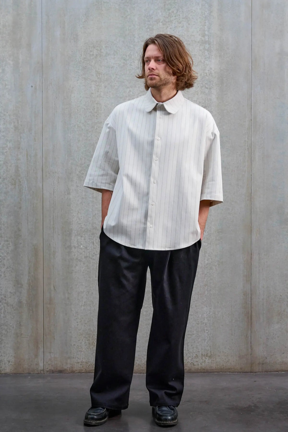Chemise arrondie oversize de la marque Aïdama, modèle Marui en coton blanc à rayures tennis. Portée par un mannequin homme et vue de face.
