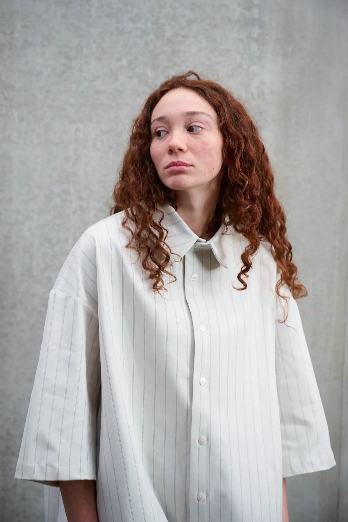 Chemise arrondie oversize de la marque Aïdama, modèle Marui en coton blanc à rayures tennis. Portée par une femme et vue de face.