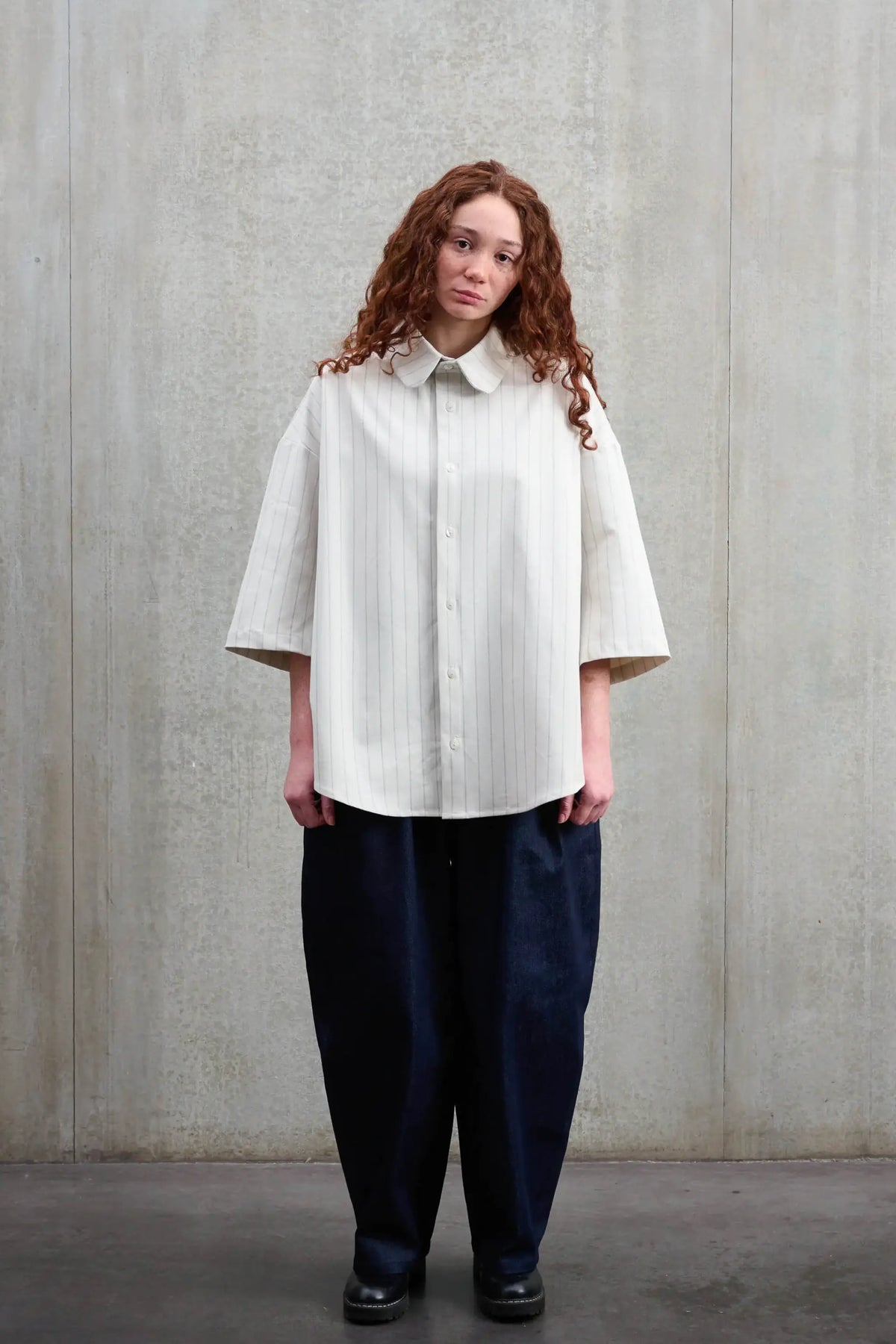 Chemise arrondie oversize de la marque Aïdama, modèle Marui en coton blanc à rayures tennis. Portée par une femme et vue de face.