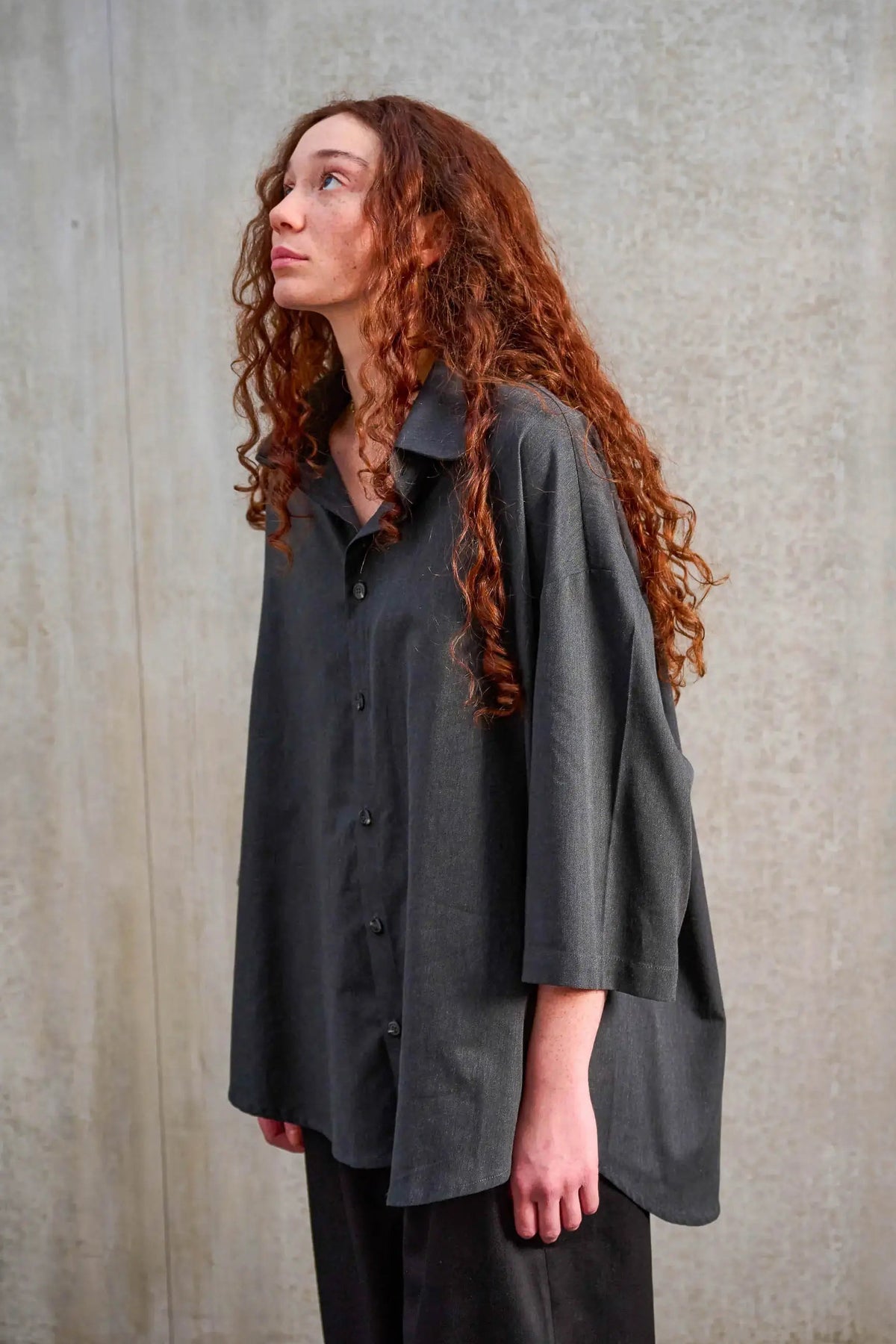 Chemise oversize arrondie de la marque Aïdama, modèle Marui en coton brossé gris foncé. Portée par une mannequin femme et vue de trois quarts.