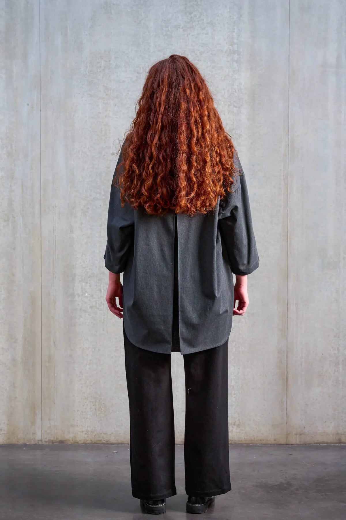 Chemise oversize arrondie de la marque Aïdama, modèle Marui en coton brossé gris foncé. Portée par une mannequin femme et vue de dos.