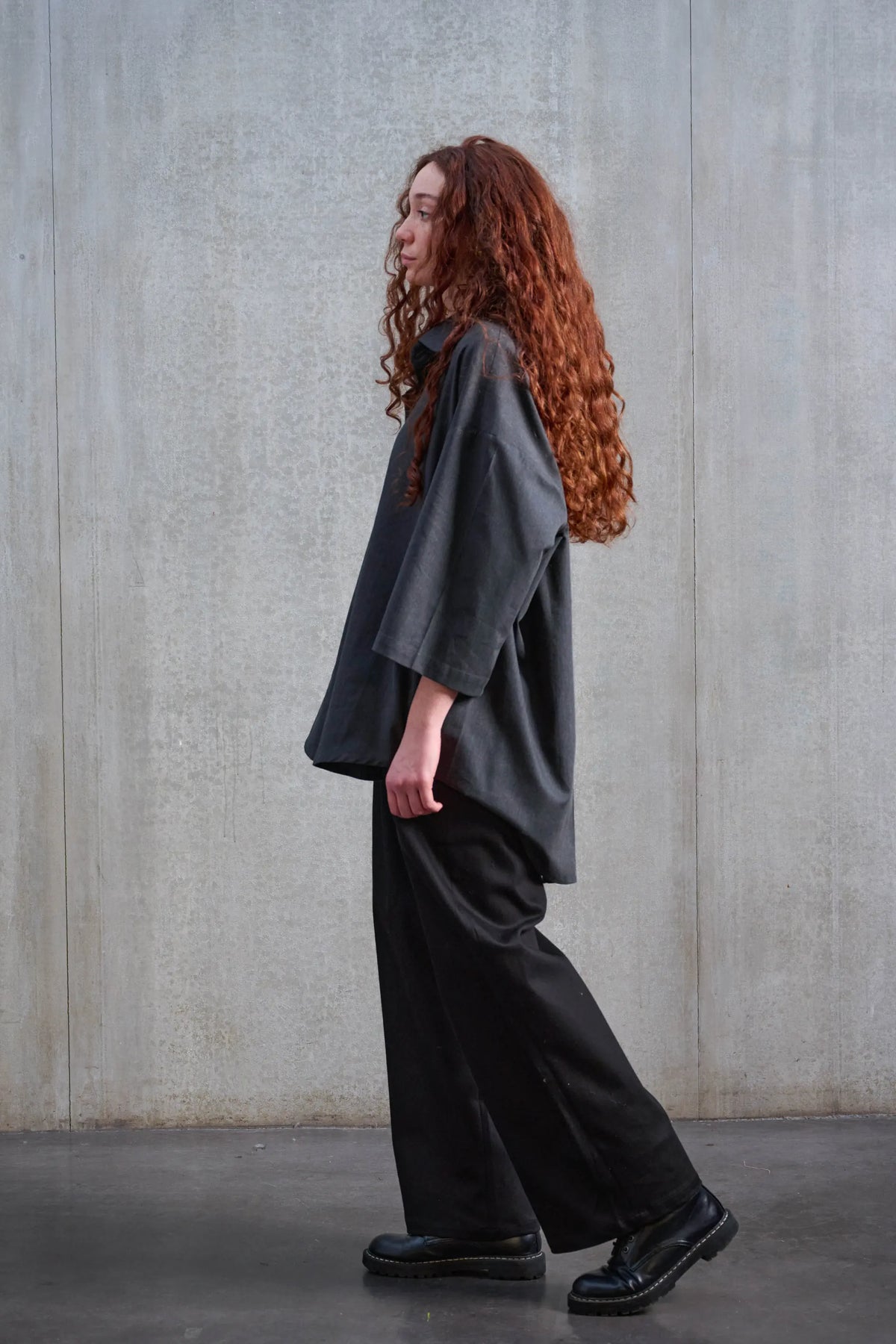 Chemise oversize arrondie de la marque Aïdama, modèle Marui en coton brossé gris foncé. Portée par une mannequin femme et vue de profil en mouvement.