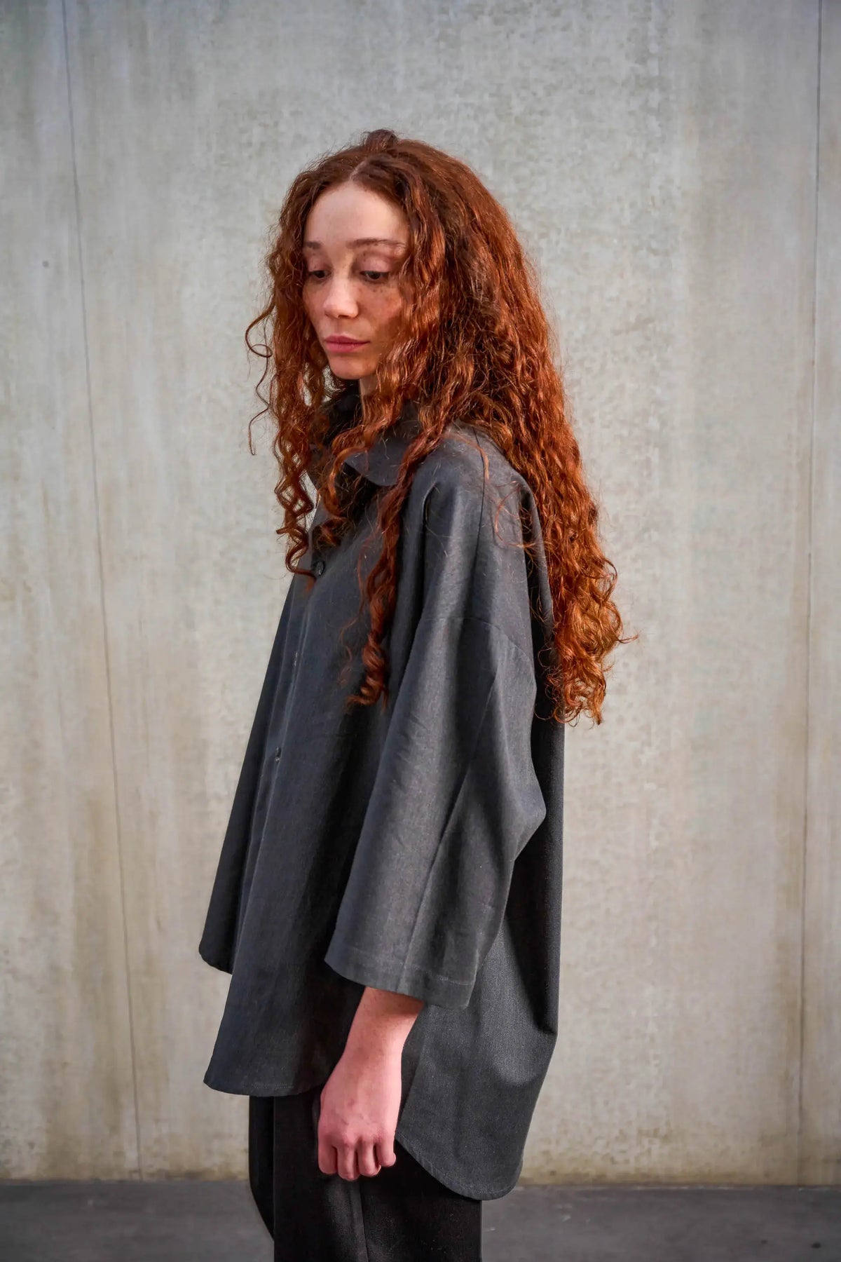 Chemise oversize arrondie de la marque Aïdama, modèle Marui en coton brossé gris foncé. Portée par une mannequin femme et vue de profil.