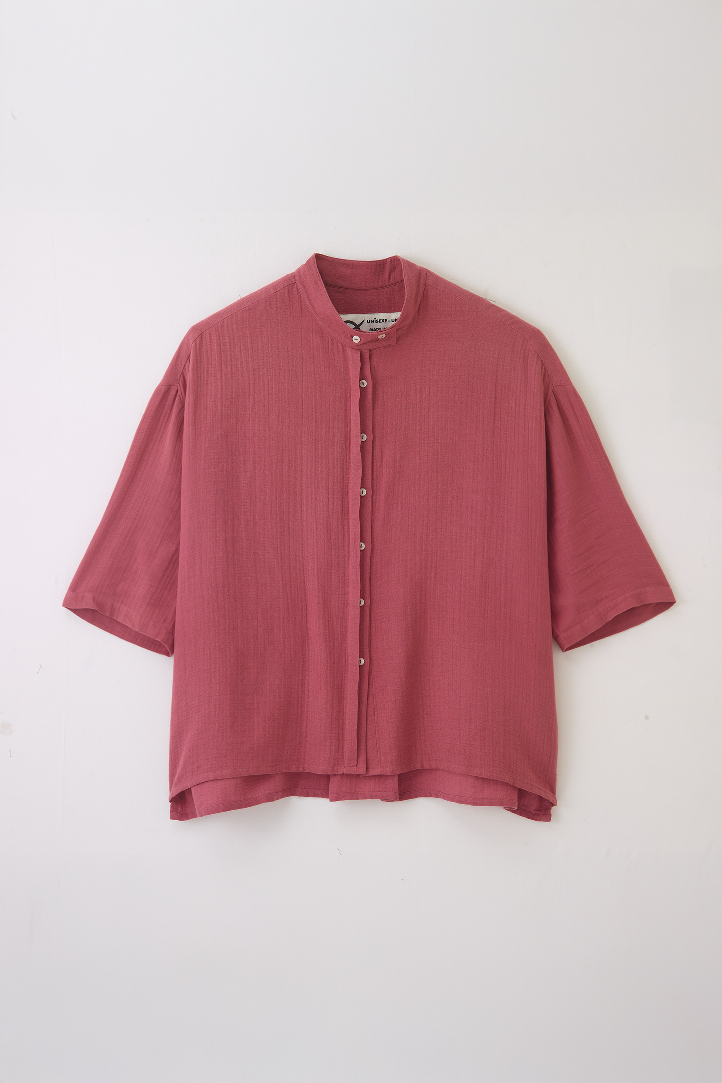 Chemise oversize à col officier de la marque aidama, modèle kita, coupe boxy en gaze de coton framboise. Posée à plat sur fond blanc.