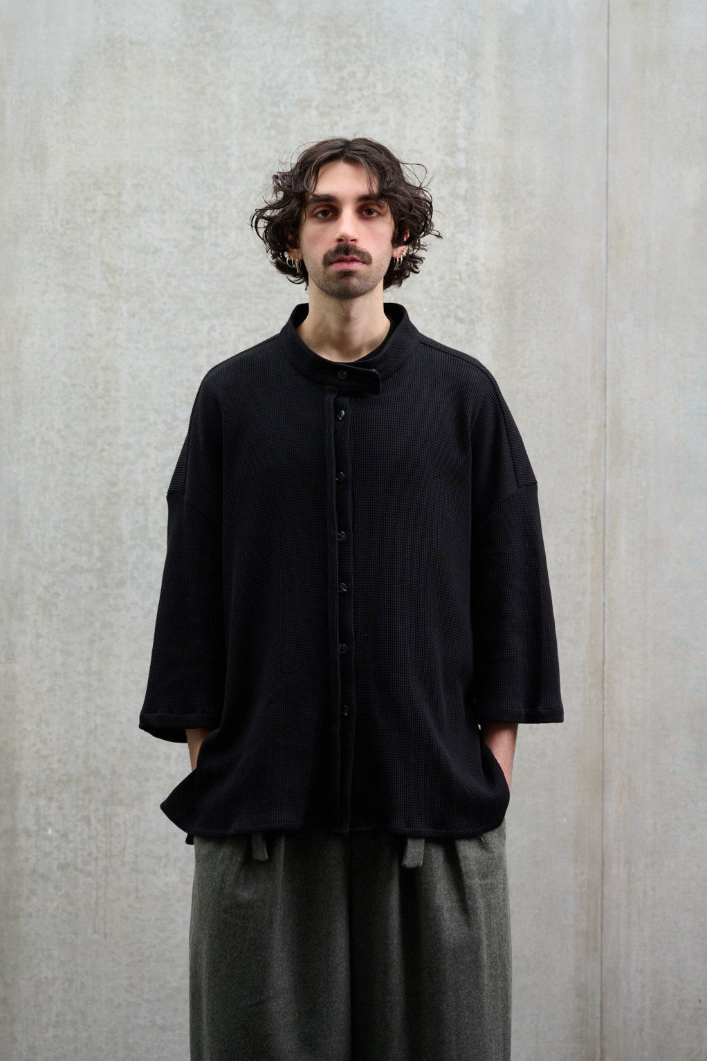 Chemise oversize à col officier, coupe boxy en coton nid d'abeille noir. Portée fermée par un mannequin homme, vue de face.