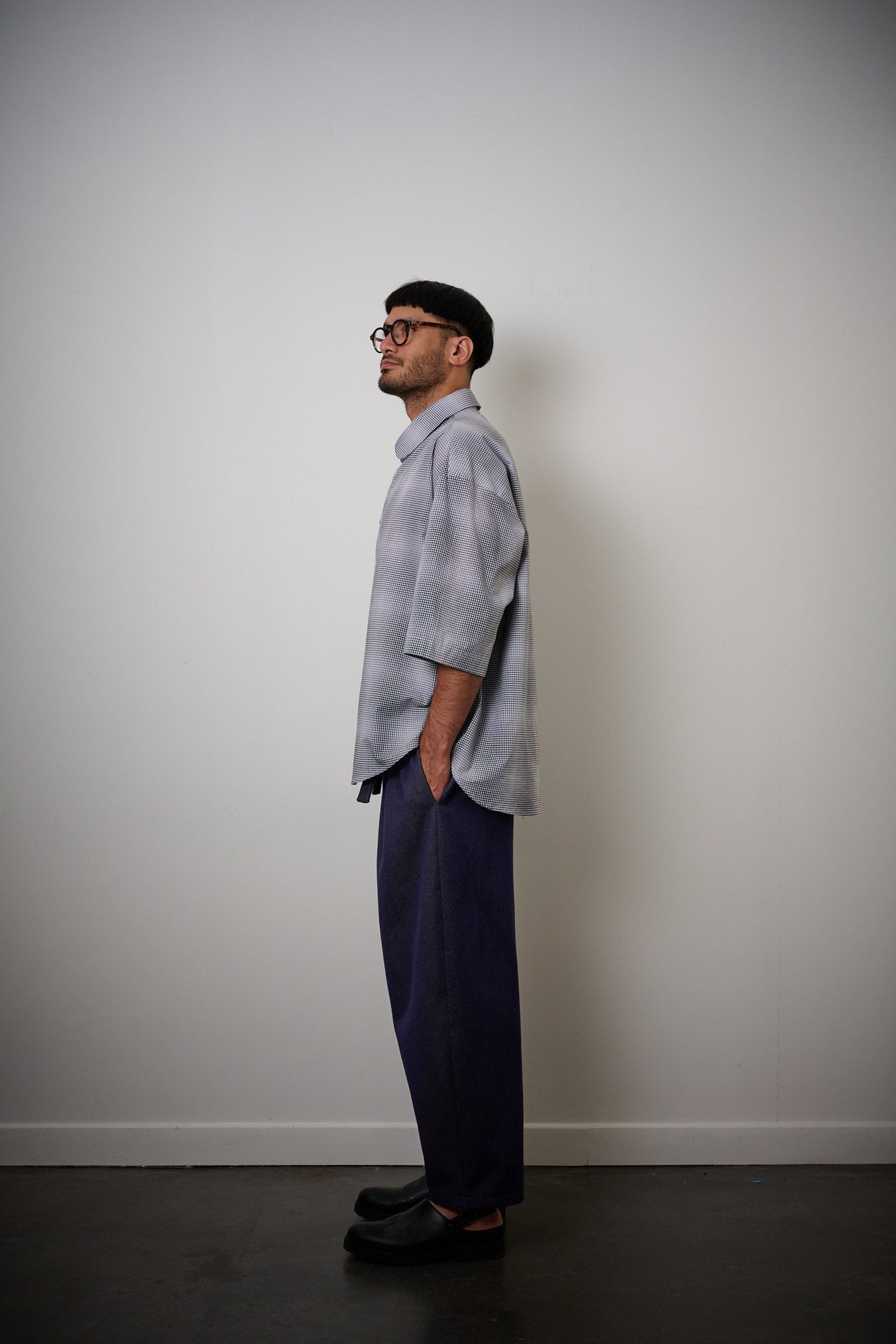 Chemise oversize à manches courtes et col club de la marque Aïdama, modèle Marui en popeline de coton à carreaux flous bleu-gris. Portée par un mannequin homme et vue de profil.