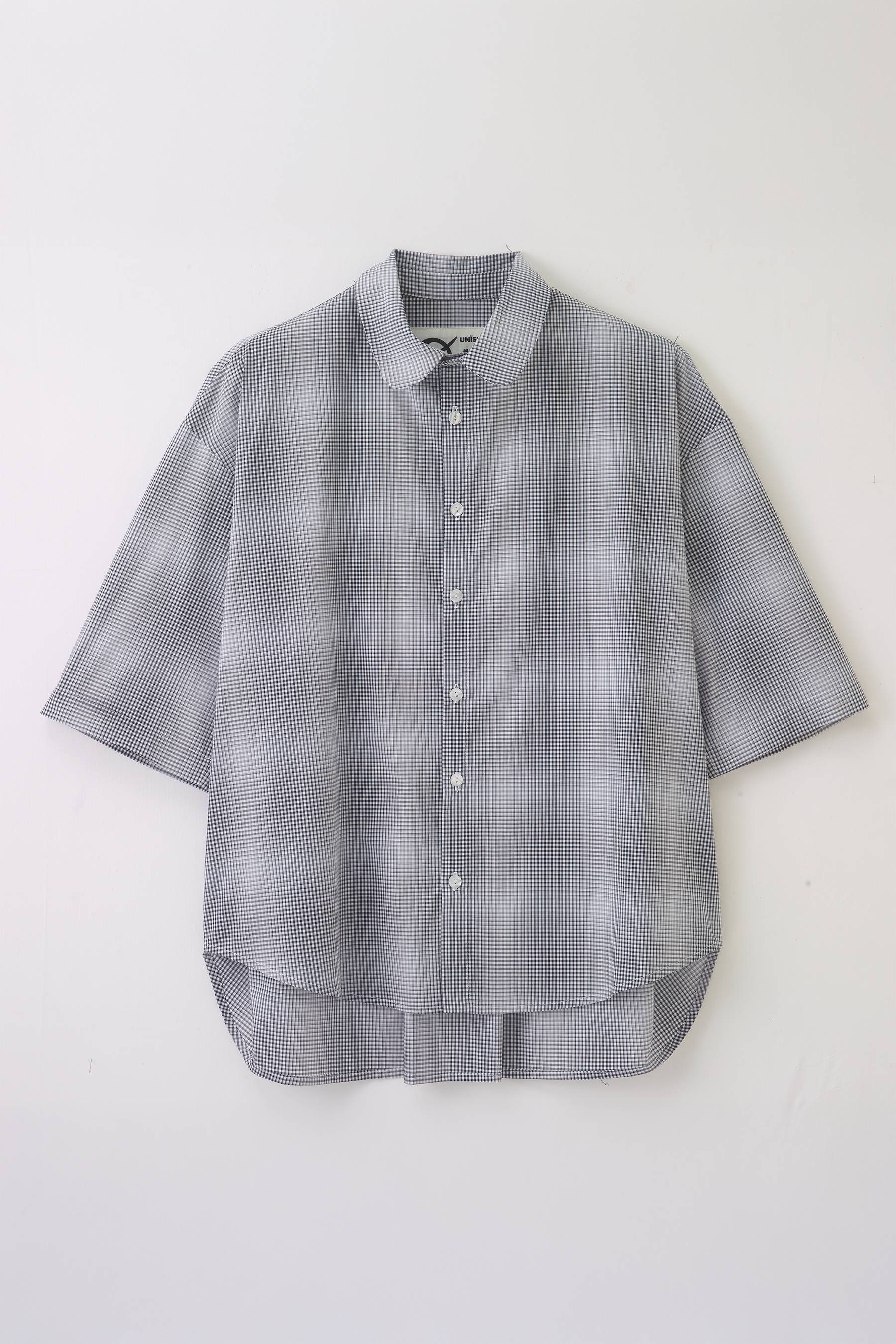 Chemise oversize à manches courtes et col club de la marque Aïdama, modèle Marui en popeline de coton à carreaux flous bleu-gris. Posée à plat sur fond blanc.