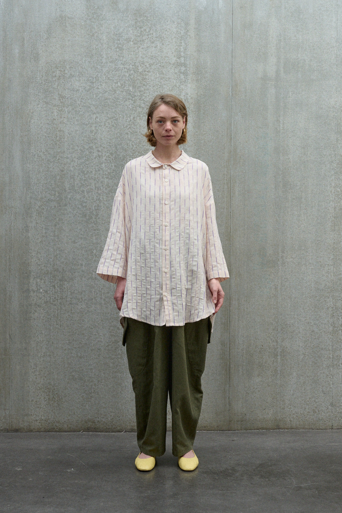 Chemise oversize à manches courtes et col officier de la marque Aïdama, modèle Kita en coton coton rose à rayures violettes. Portée par une mannequin femme et vue de face.