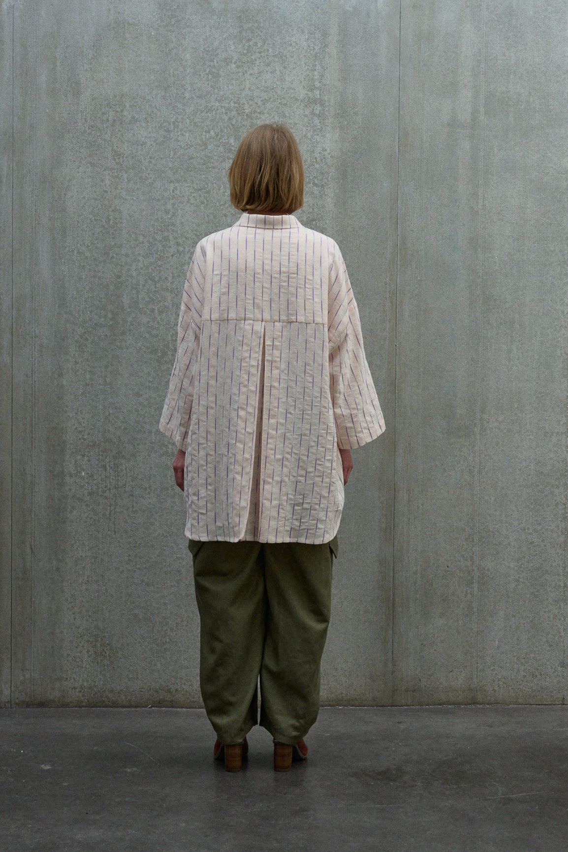Chemise oversize à manches courtes et col officier de la marque Aïdama, modèle Kita en coton coton rose à rayures violettes. Portée par une mannequin femme et vue de dos.