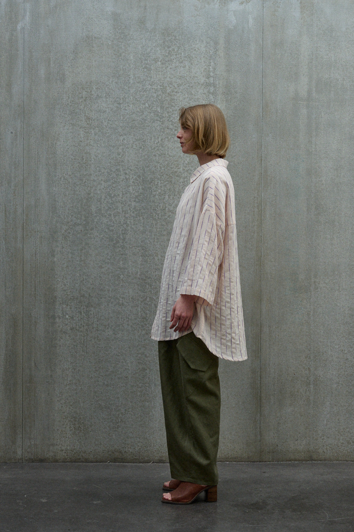Chemise oversize à manches courtes et col officier de la marque Aïdama, modèle Kita en coton coton rose à rayures violettes. Portée par une mannequin femme et vue de profil.