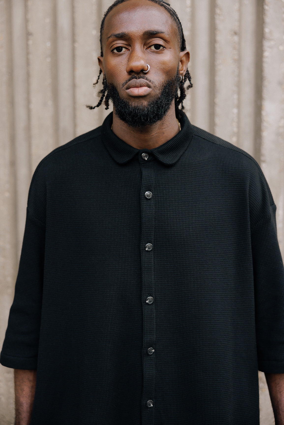 Chemise oversize à manches courtes et col club de la marque Aïdama, modèle Marui en coton nid d’abeille noir. Portée par un mannequin homme et vue de face.