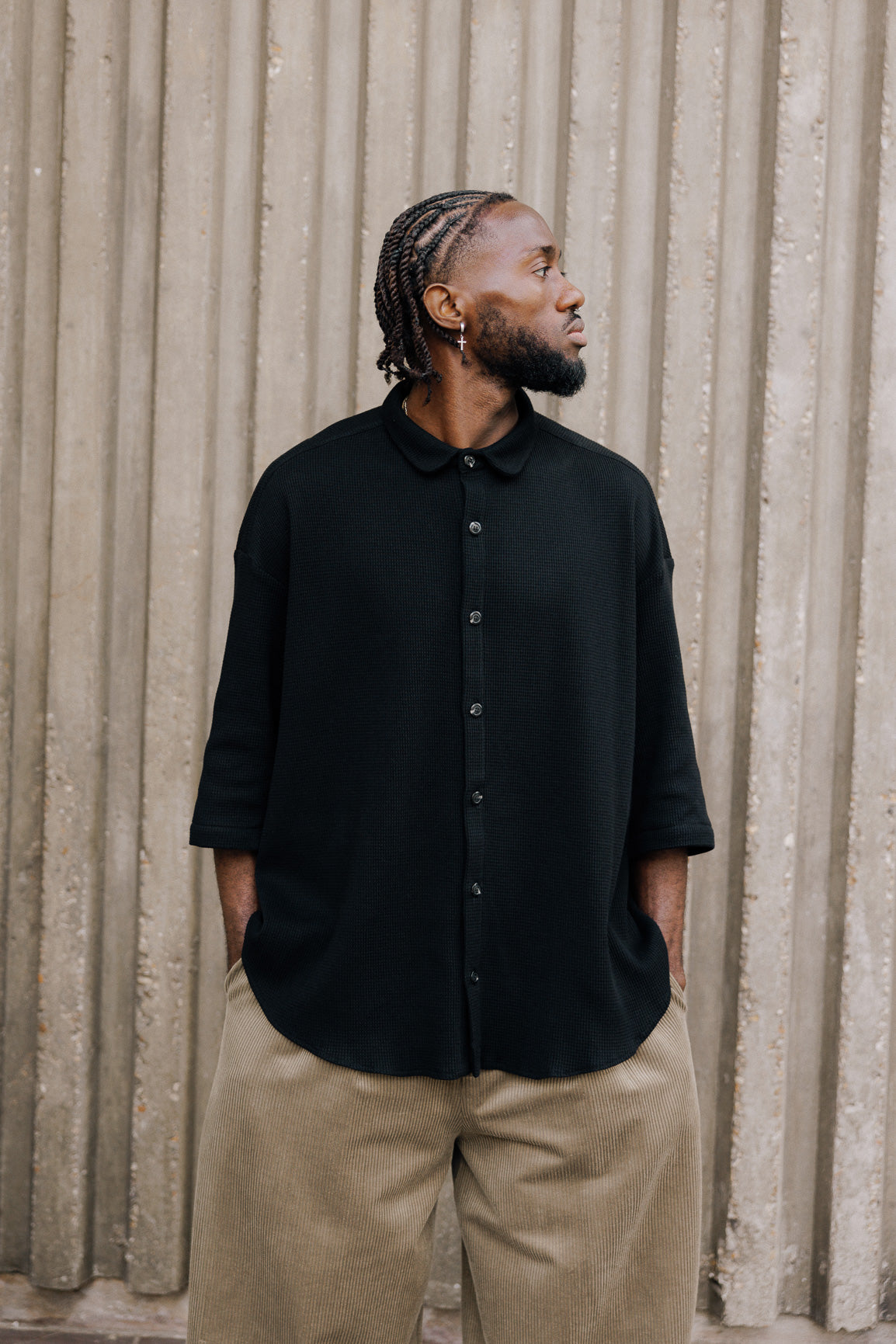 Chemise oversize à manches courtes et col club de la marque Aïdama, modèle Marui en coton nid d’abeille noir. Portée par un mannequin homme et vue de face.