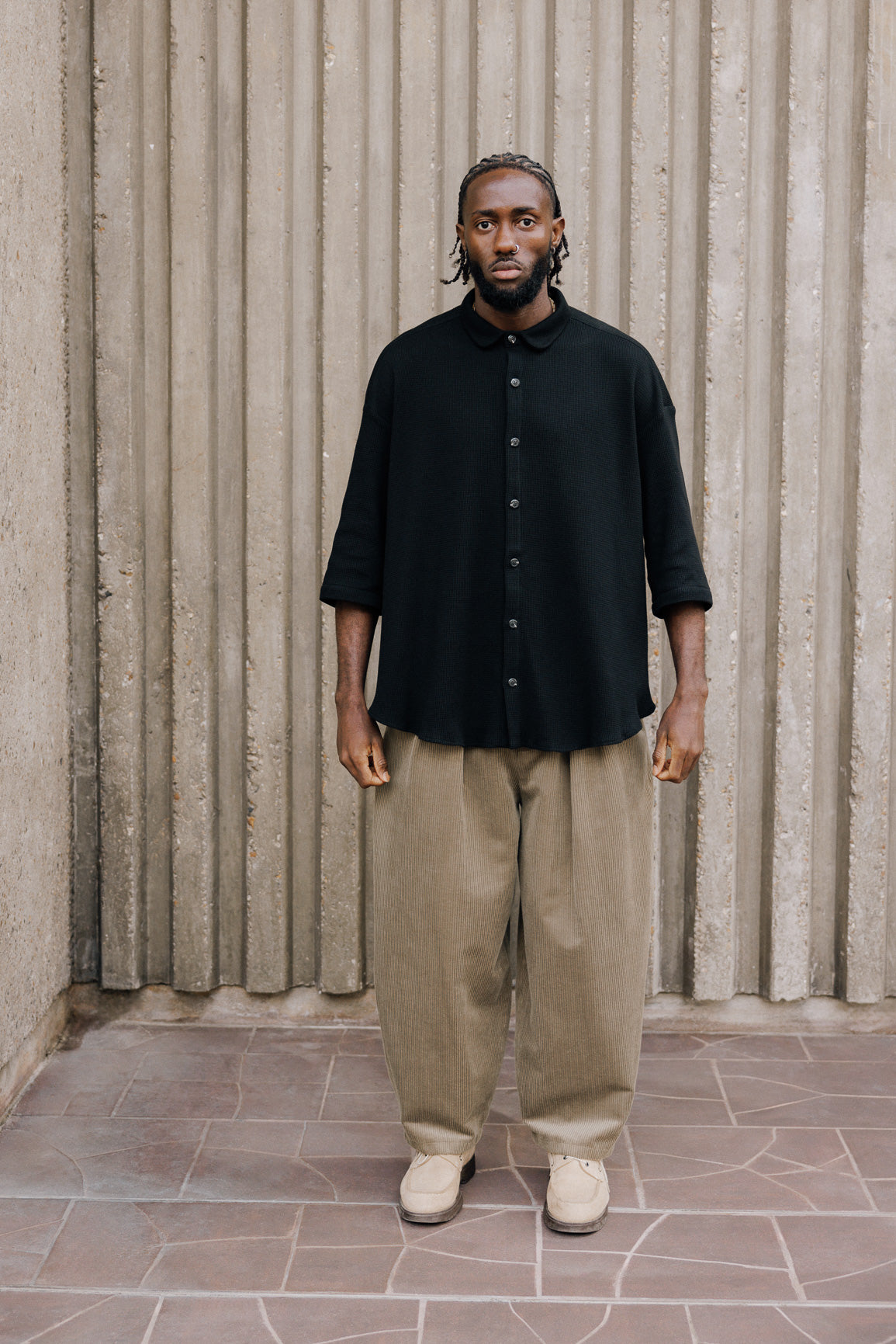 Chemise oversize à manches courtes et col club de la marque Aïdama, modèle Marui en coton nid d’abeille noir. Portée par un mannequin homme et vue de face.