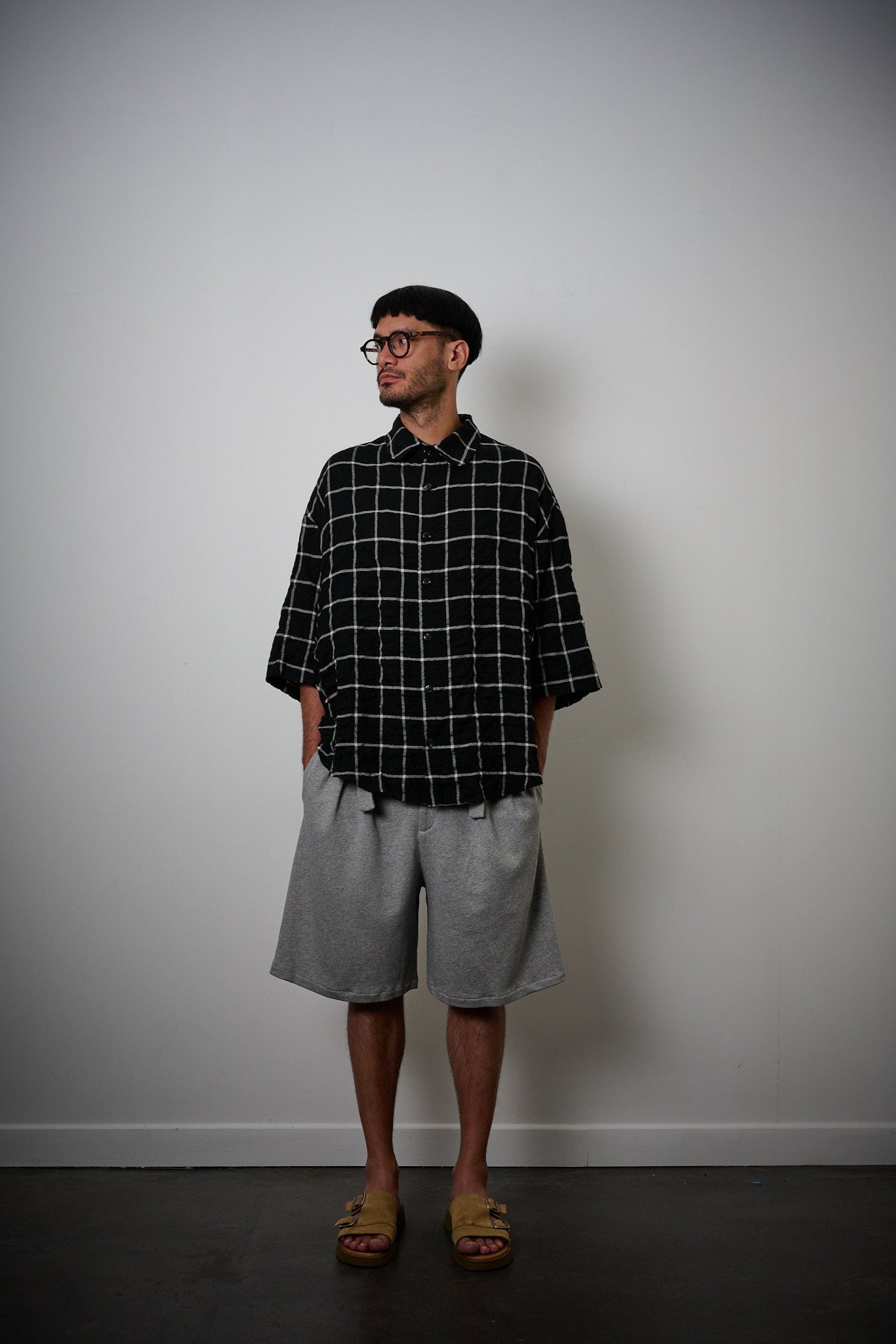 Chemise oversize à manches courtes et col club de la marque Aïdama, modèle Marui en coton seersucker à motif tartan & chevrons noir et blanc. Portée par un mannequin homme et vue de face. 