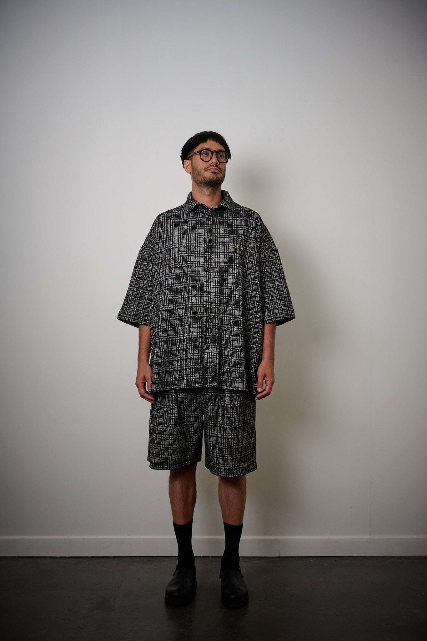 Chemise oversize à manches courtes et col club de la marque Aïdama, modèle Oba en laine à motif géométrique noir et blanc. Portée par un mannequin homme et vue de face.