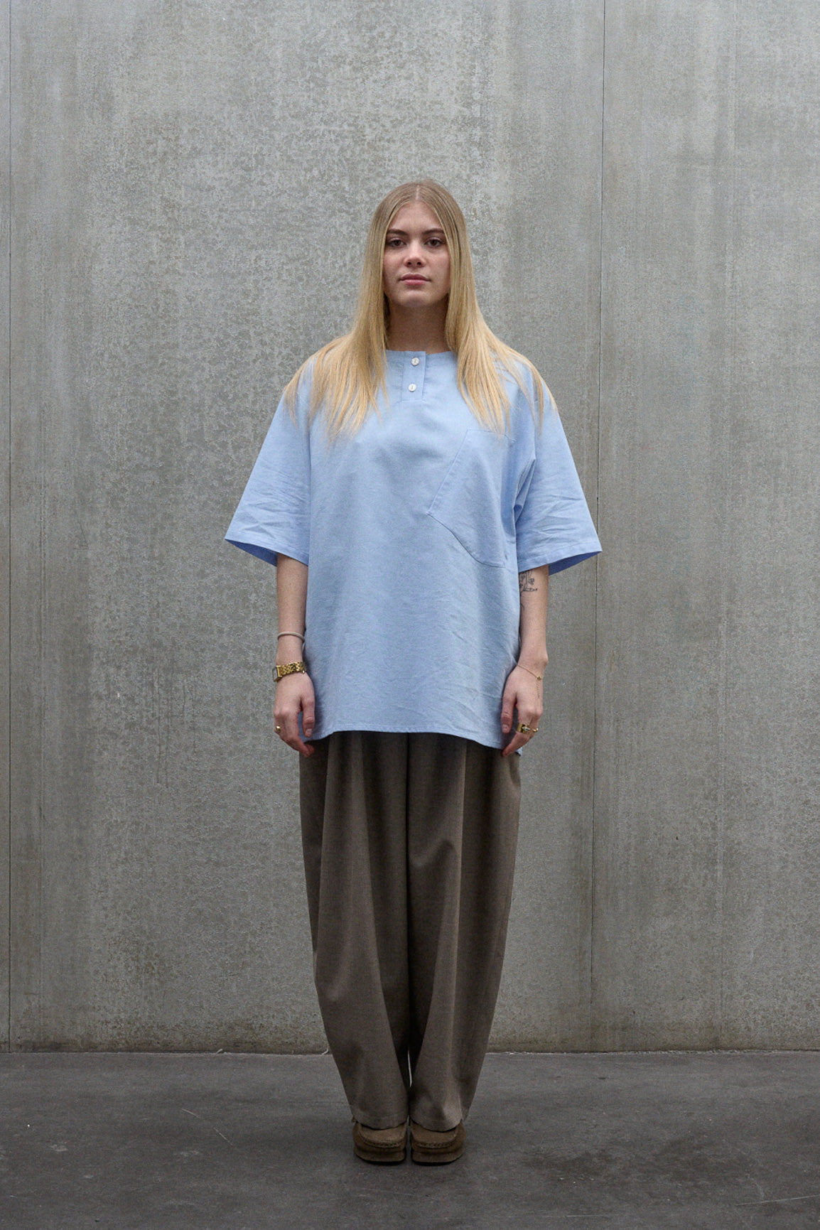 Chemise popover oversize à col tunisien et poche poitrine de la marque Aïdama, en coton piqué bleu. Portée par une mannequin femme et vue de face.
