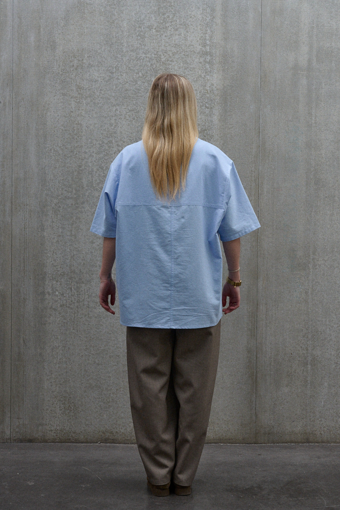 Chemise popover oversize à col tunisien et poche poitrine de la marque Aïdama, en coton piqué bleu. Portée par une mannequin femme et vue de dos.