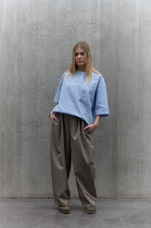 Chemise popover oversize à col tunisien et poche poitrine de la marque Aïdama, en coton piqué bleu. Portée par une mannequin femme et vue de face.