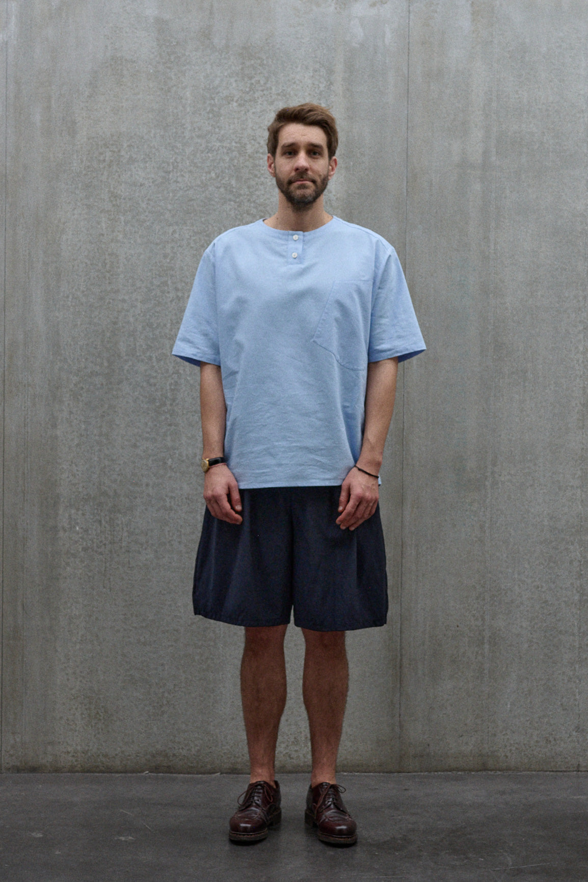 Chemise popover oversize à col tunisien et poche poitrine de la marque Aïdama, en coton piqué bleu. Portée par un mannequin homme et vue de face.