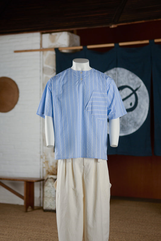 Chemise popover oversize à col tunisien et poche poitrine de la marque Aïdama, en coton bleu à rayures. Vue de face sur mannequin.