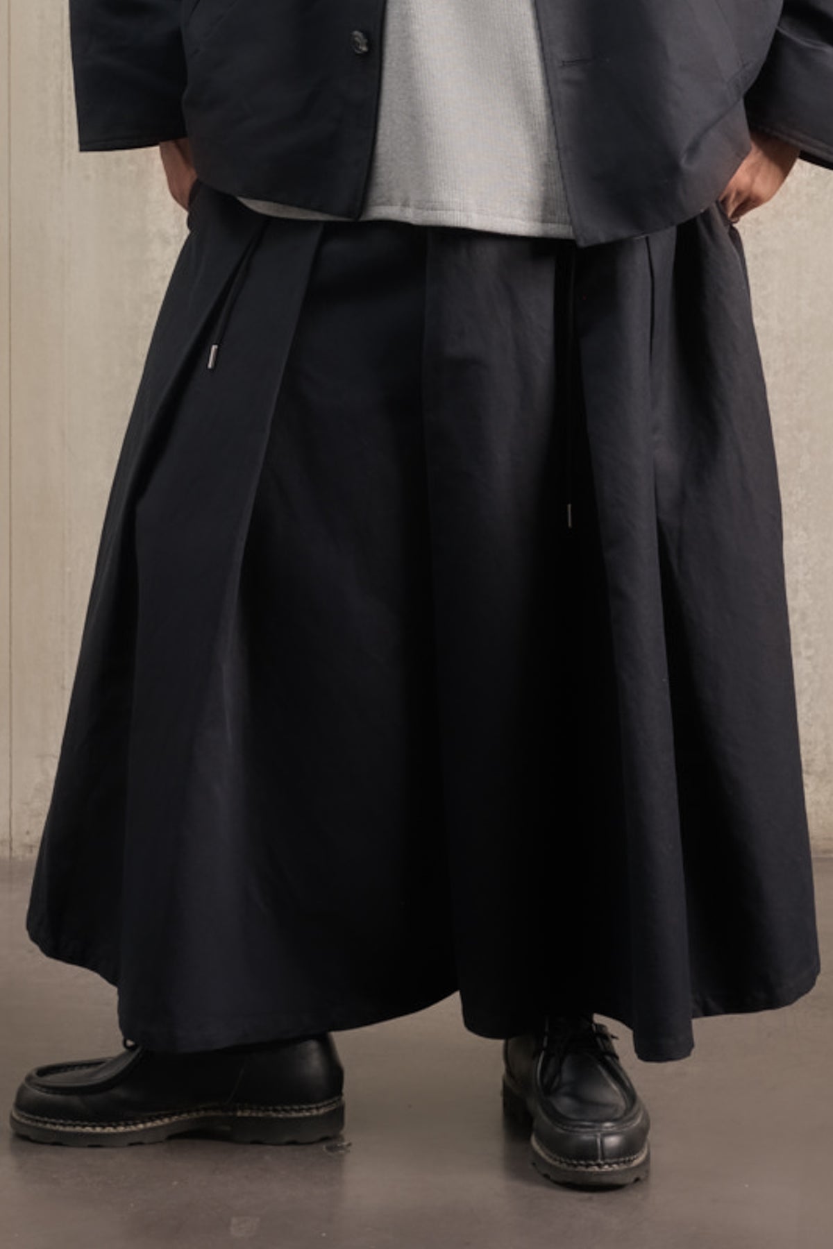 Jupe culotte oversize de la marque Aïdama, modèle Hakama en coton & lin noir. Porté par un mannequin homme et vu de face centré sur les jambes.