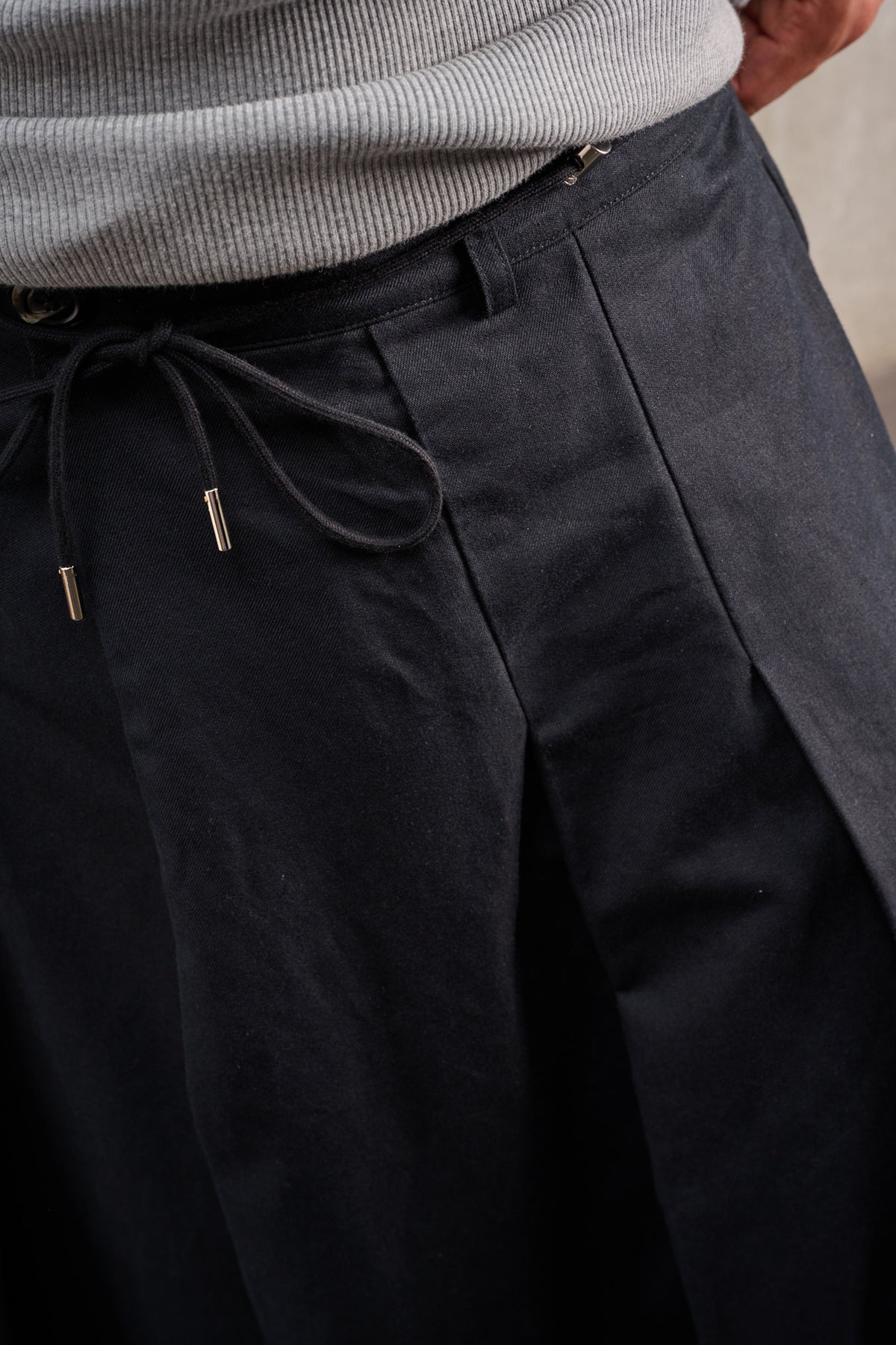 Jupe culotte oversize de la marque Aïdama, modèle Hakama en coton & lin noir. Porté par un mannequin homme et vu de face zoomé sur le cordon.
