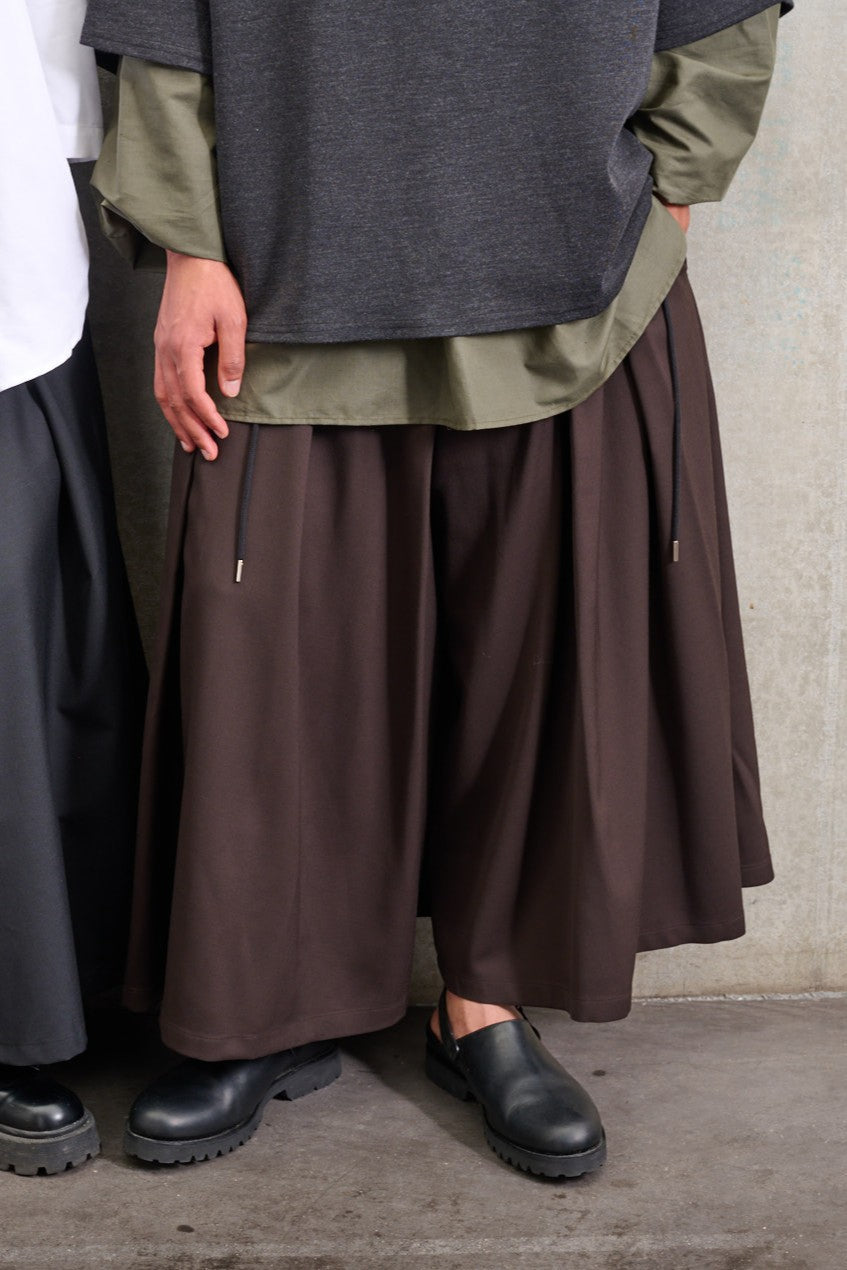 Jupe culotte oversize de la marque Aïdama, modèle Hakama en laine froide marron, portée par un modèle homme et vue zoomée sur les jambes.