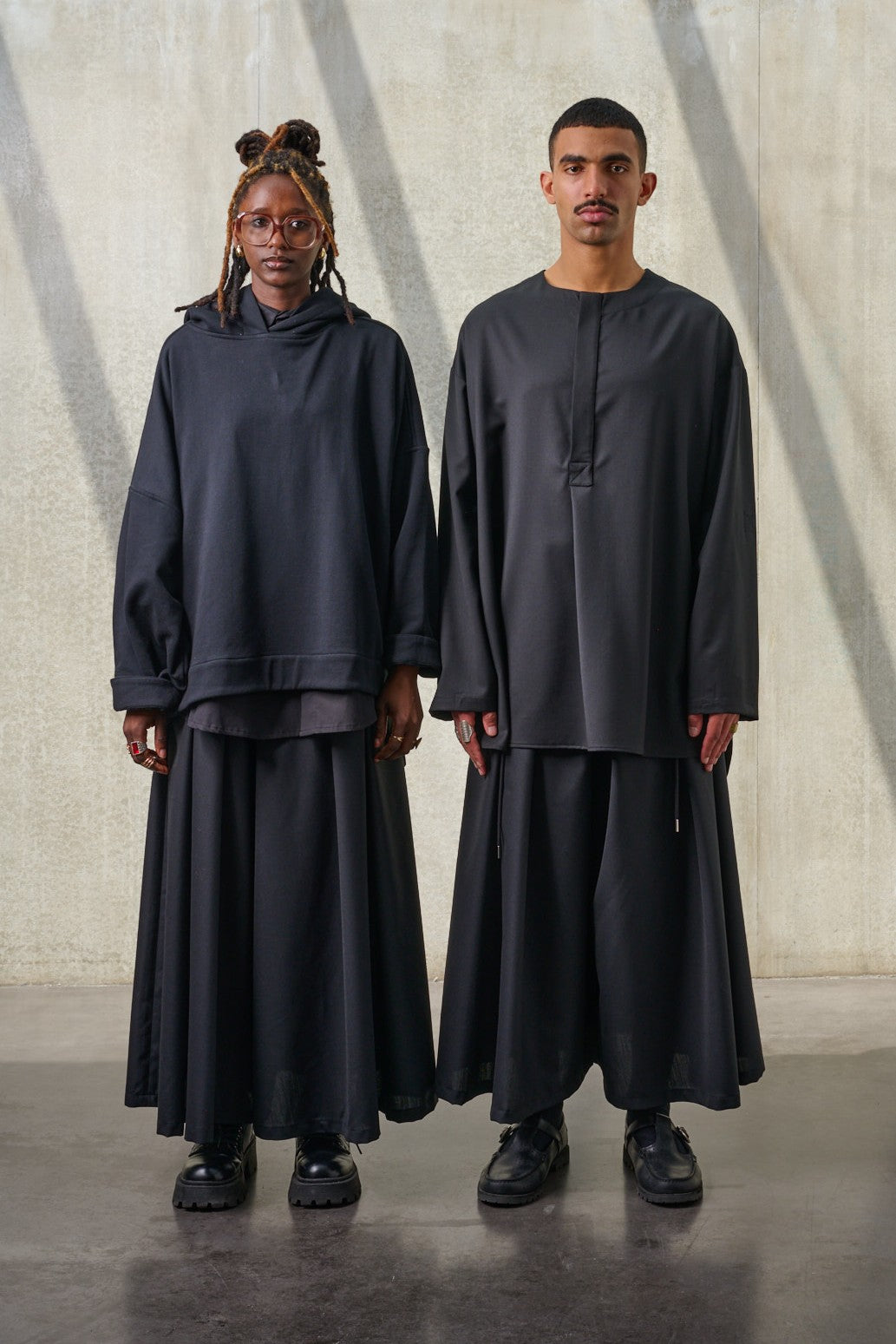 Jupes culottes oversize de la marque Aïdama, modèle Hakama en laine froide noire, portée par un modèle homme et un modèle femme et vues de face.