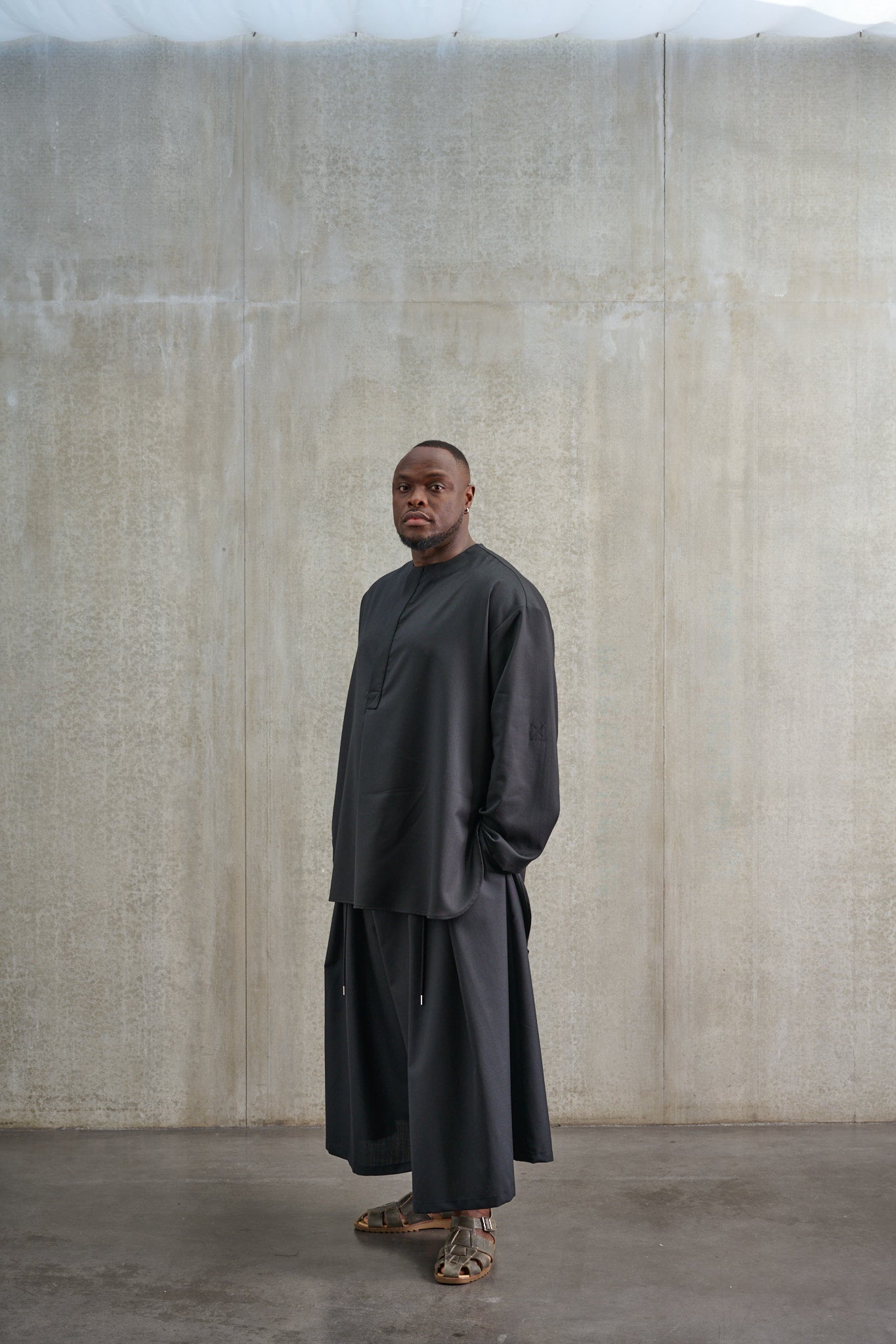 Jupe culotte oversize de la marque Aïdama, modèle Hakama en laine froide noire, portée par un modèle homme et vue de trois quarts.
