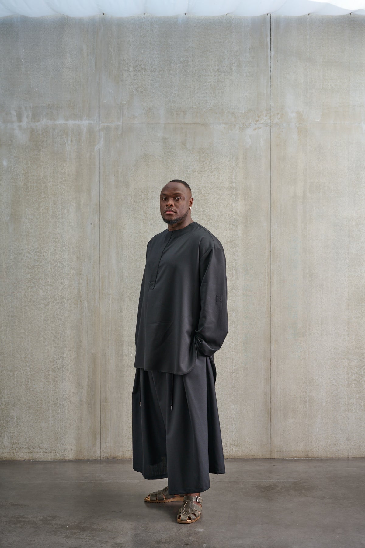 Jupe culotte oversize de la marque Aïdama, modèle Hakama en laine froide noire, portée par un modèle homme et vue de trois quarts.